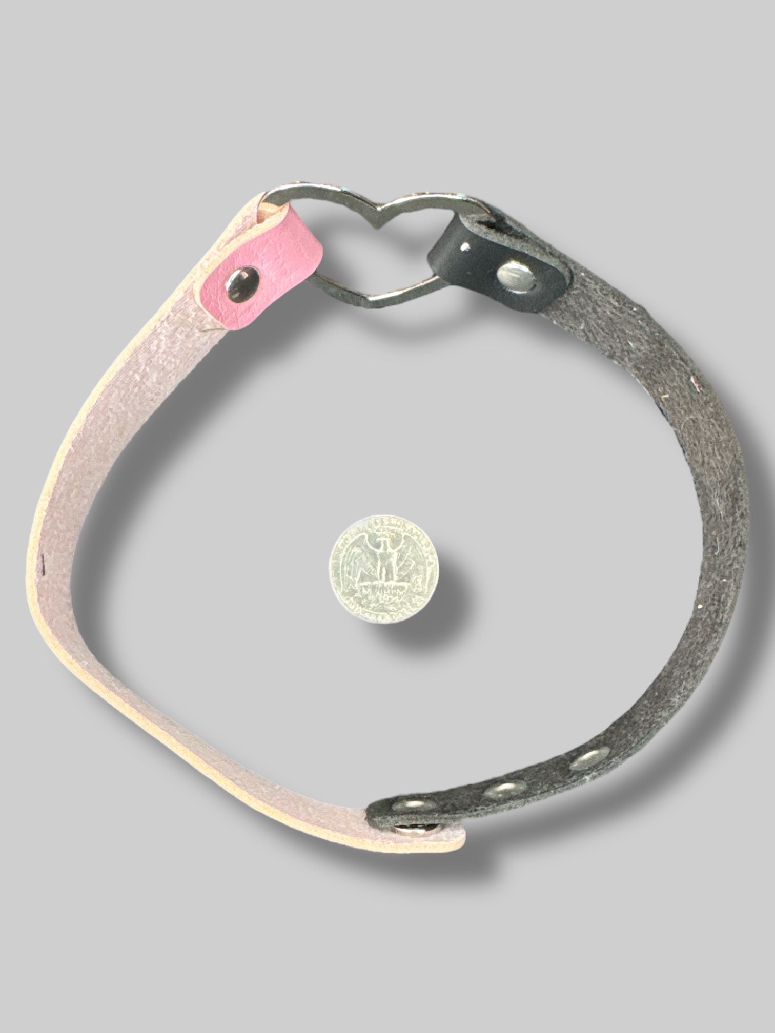Black and pink leather choker with heart ring in middle, and snap button closure