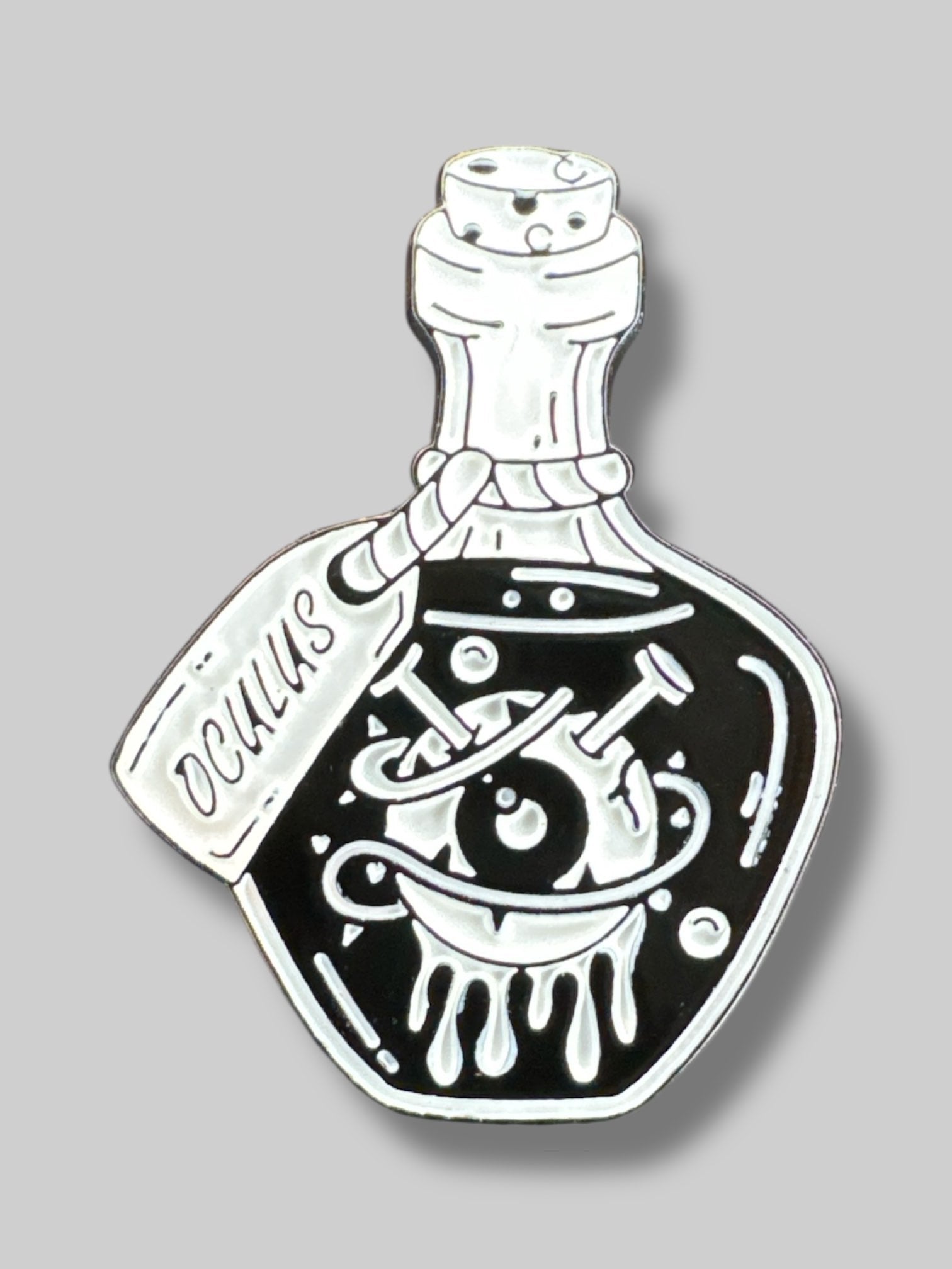 Small black and white pin with potion bottle and eyeball