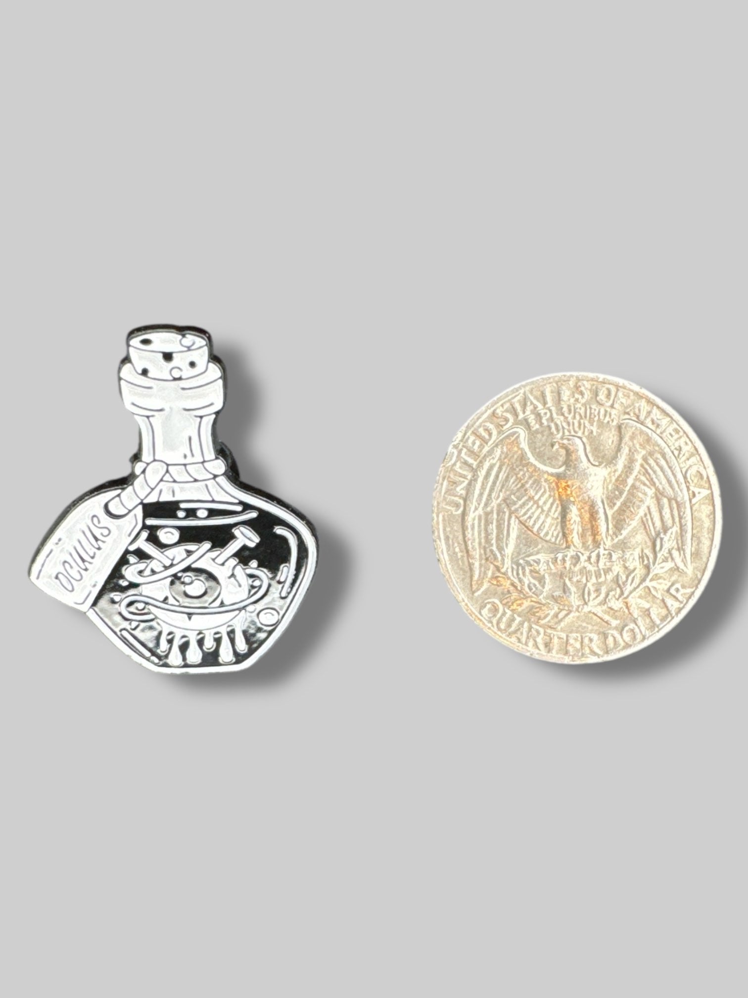 Small black and white pin with potion bottle and eyeball
