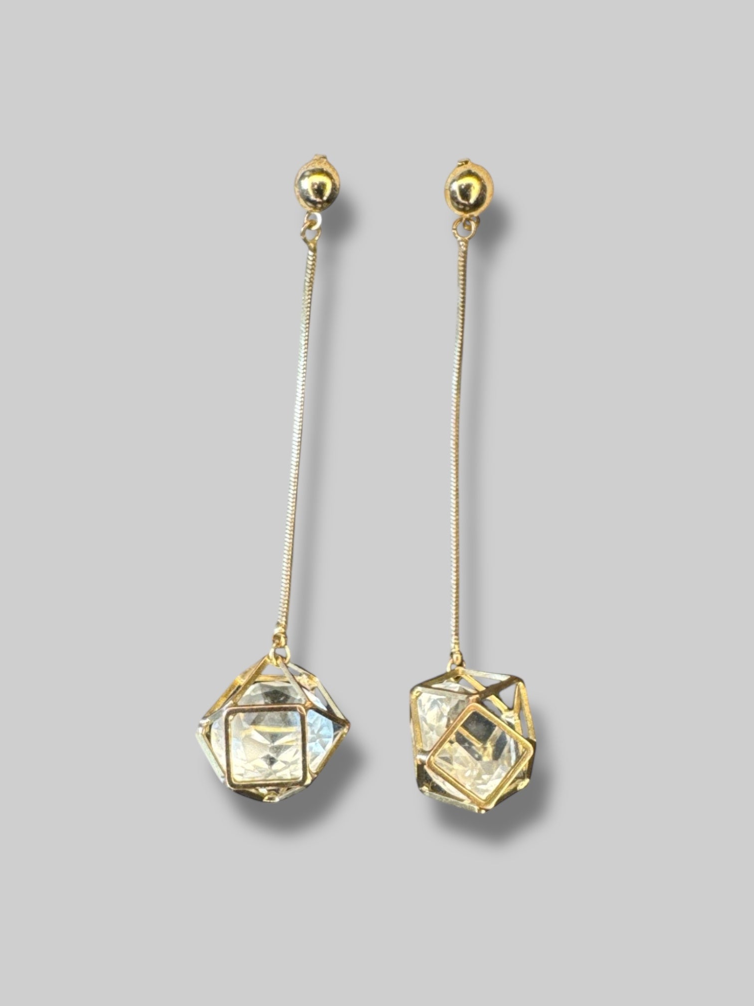 Gold tone dangly geometric cage earrings with faux clear gem inside