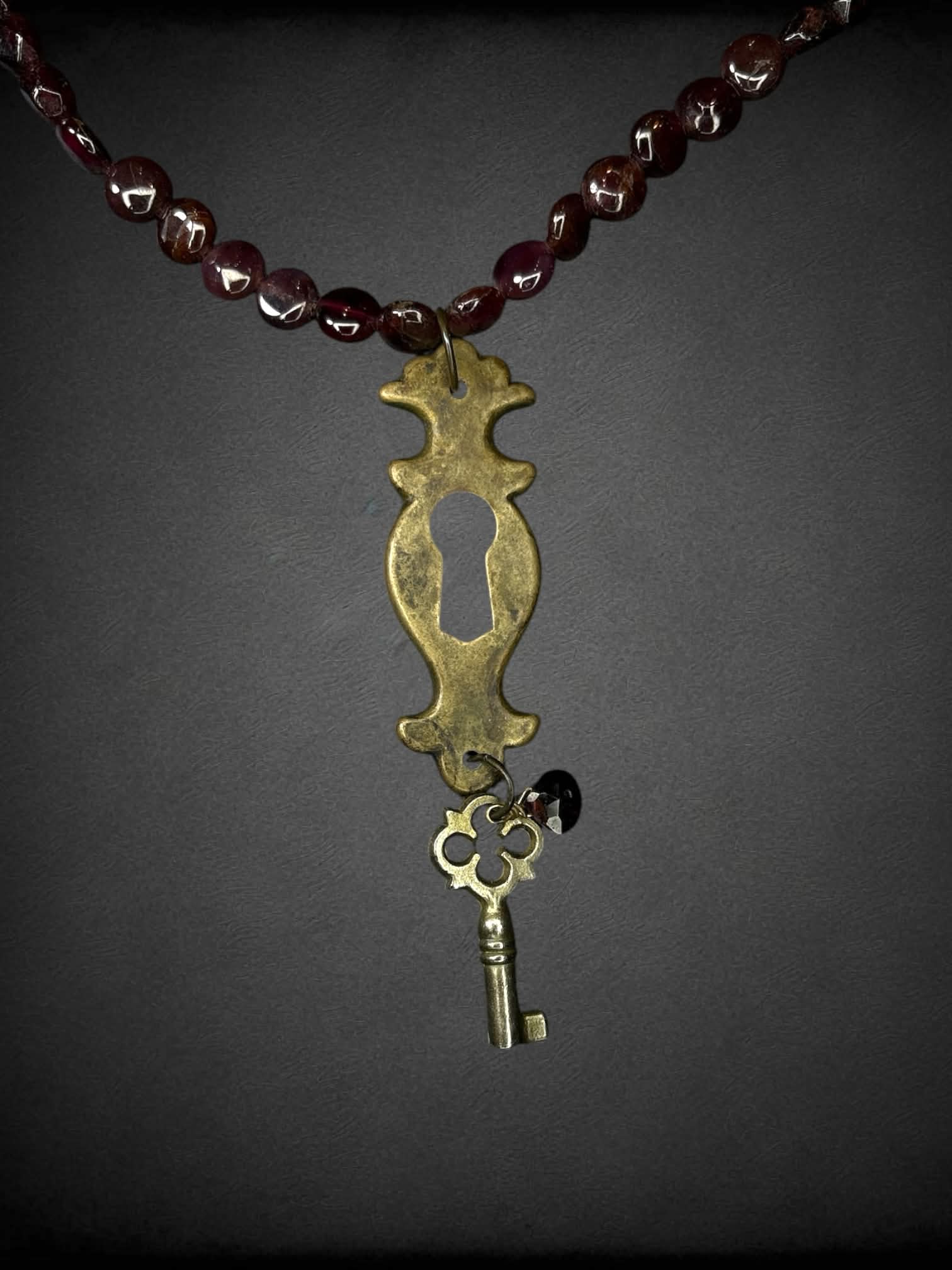Garnet beaded necklace with keyhole & key charm, and metallic spiral clasp