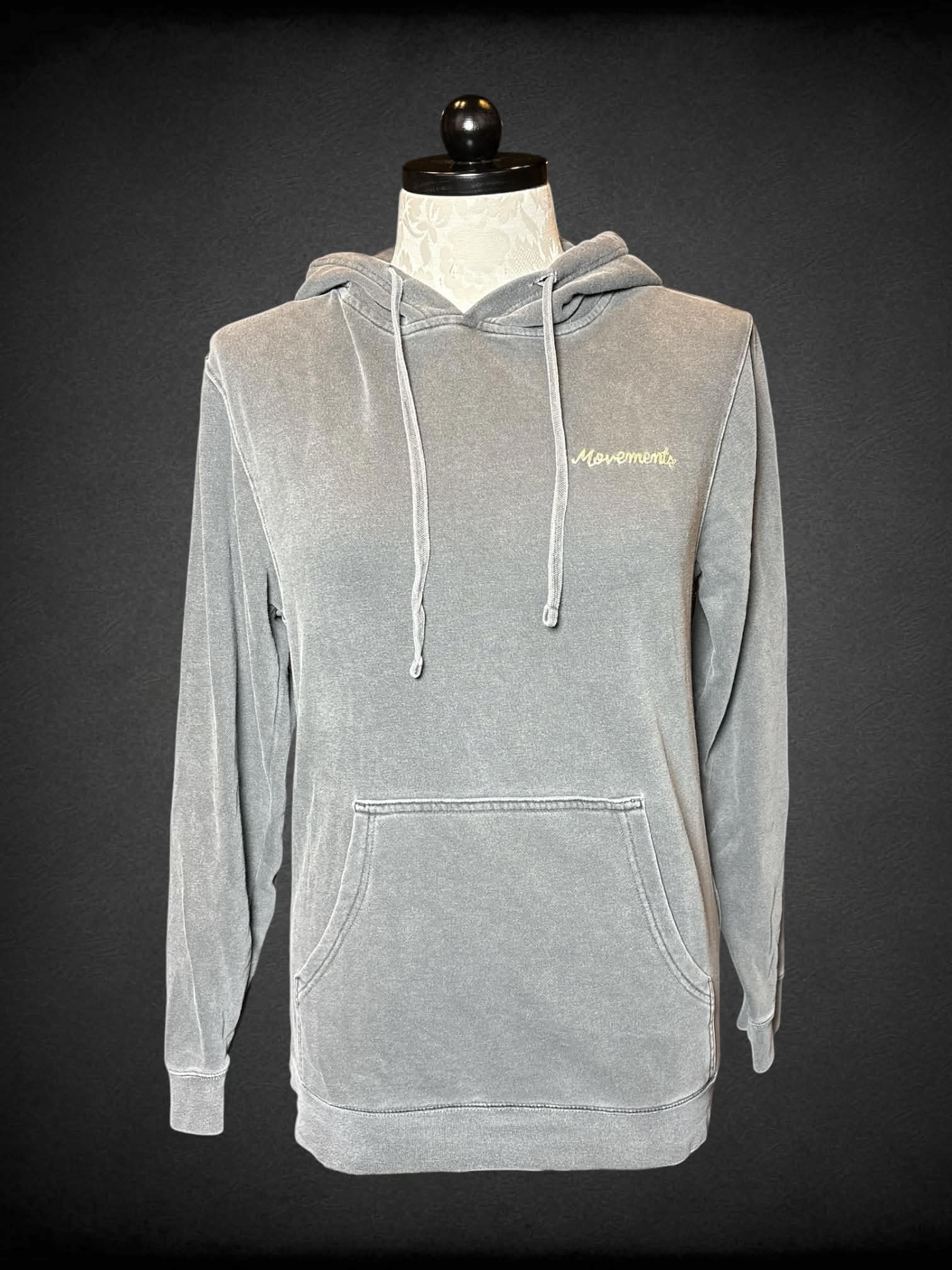 1X Independent Trading Company grey pullover hoodie with embroidered “Movements” on front and “You’ll Be Just Fine” writing on back