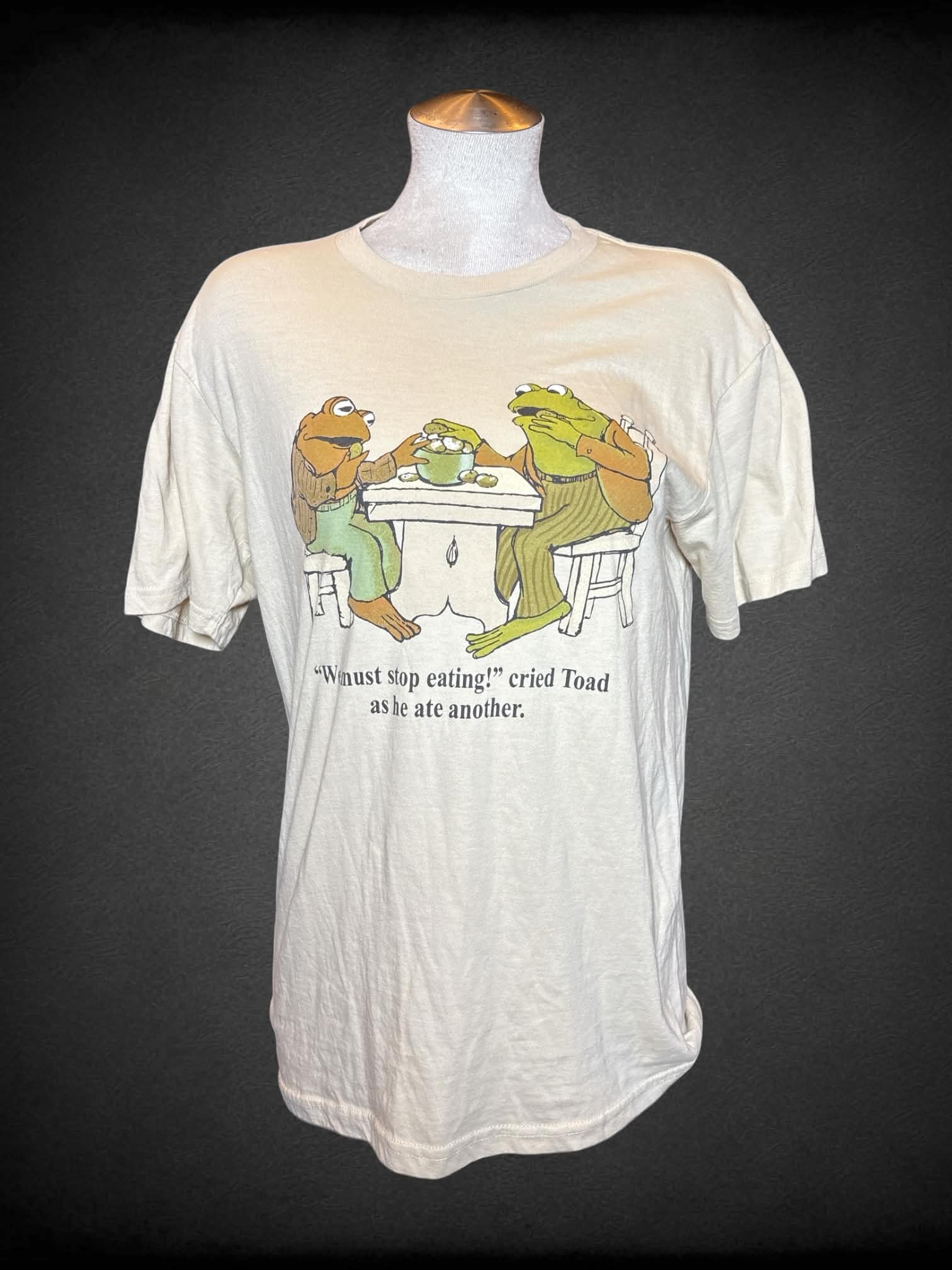 L Frog and Toad tan t shirt with “Frog and Toad” graphic on front