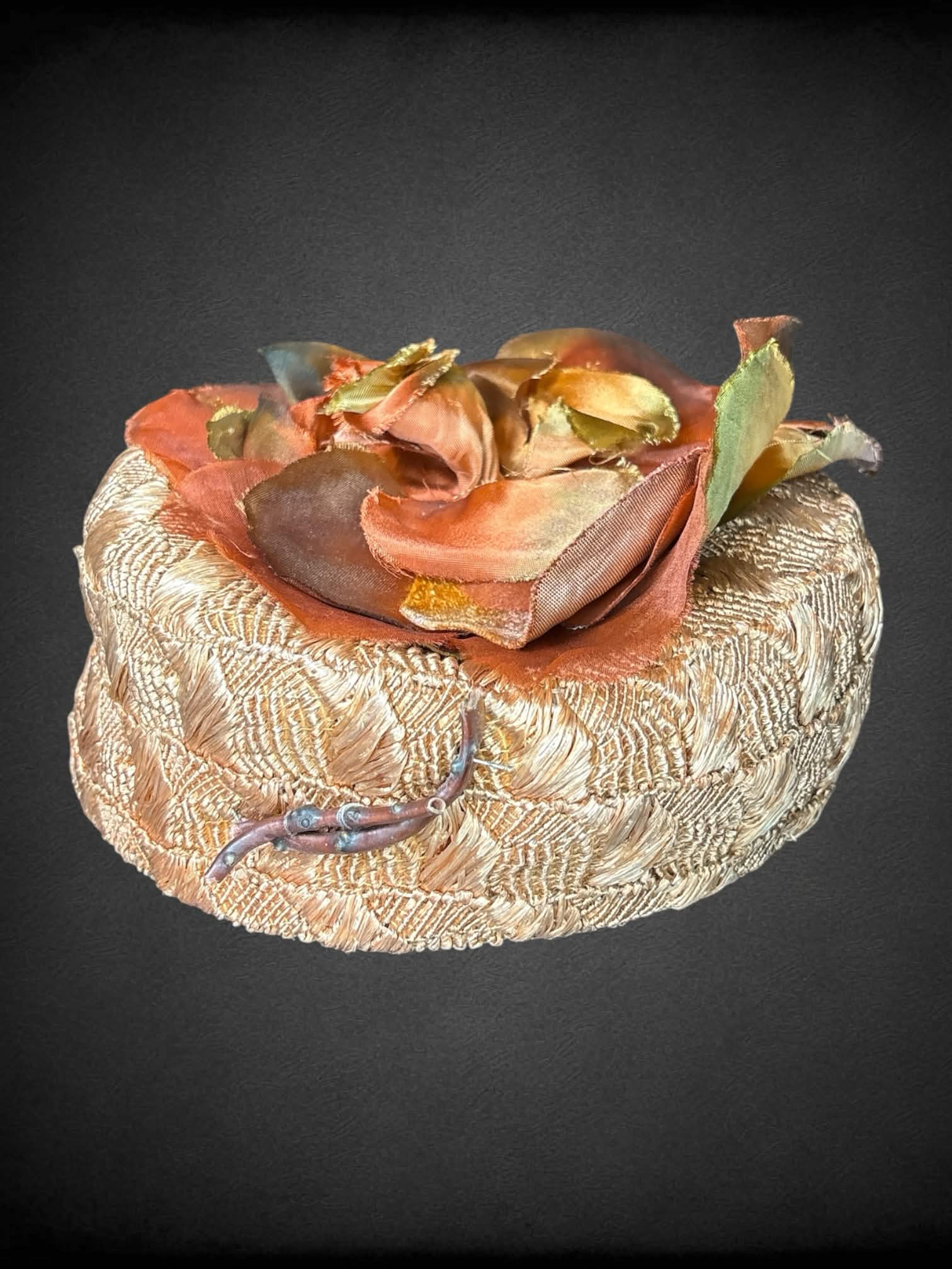 Vintage brown woven hat with orange flower design on top, and decorative sticks on front