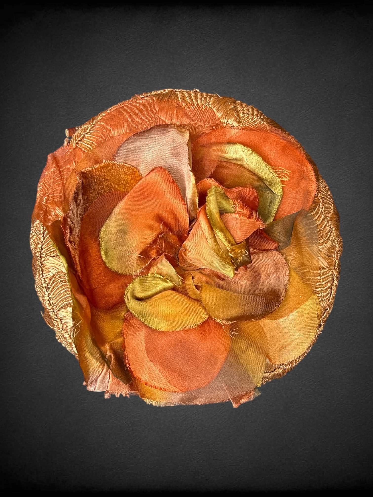 Vintage brown woven hat with orange flower design on top, and decorative sticks on front