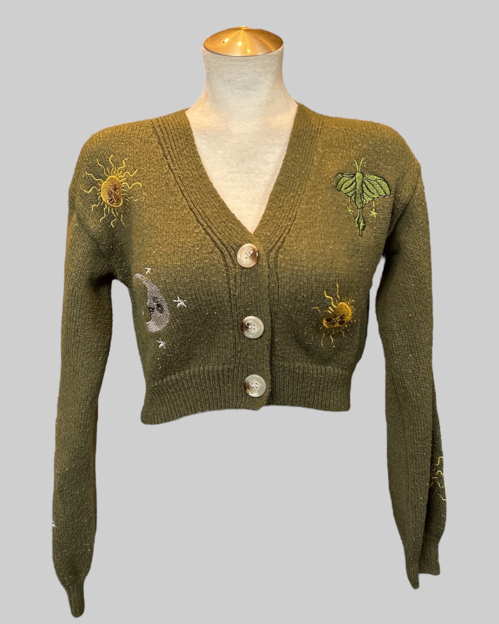 M green knit cardigan with moon, suns, stars, and leaves