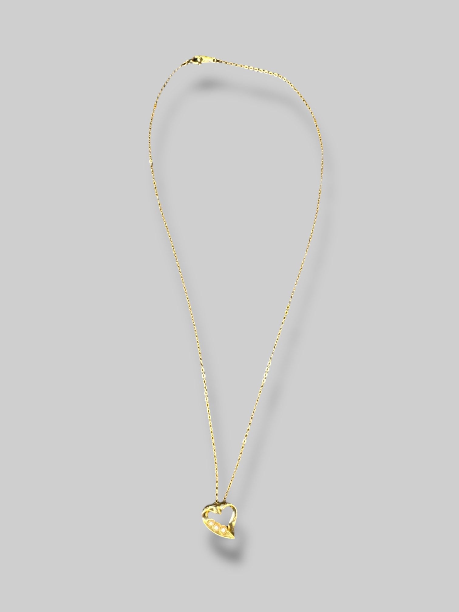 Gold tone, necklace with heart shape, pendant, and pearl details