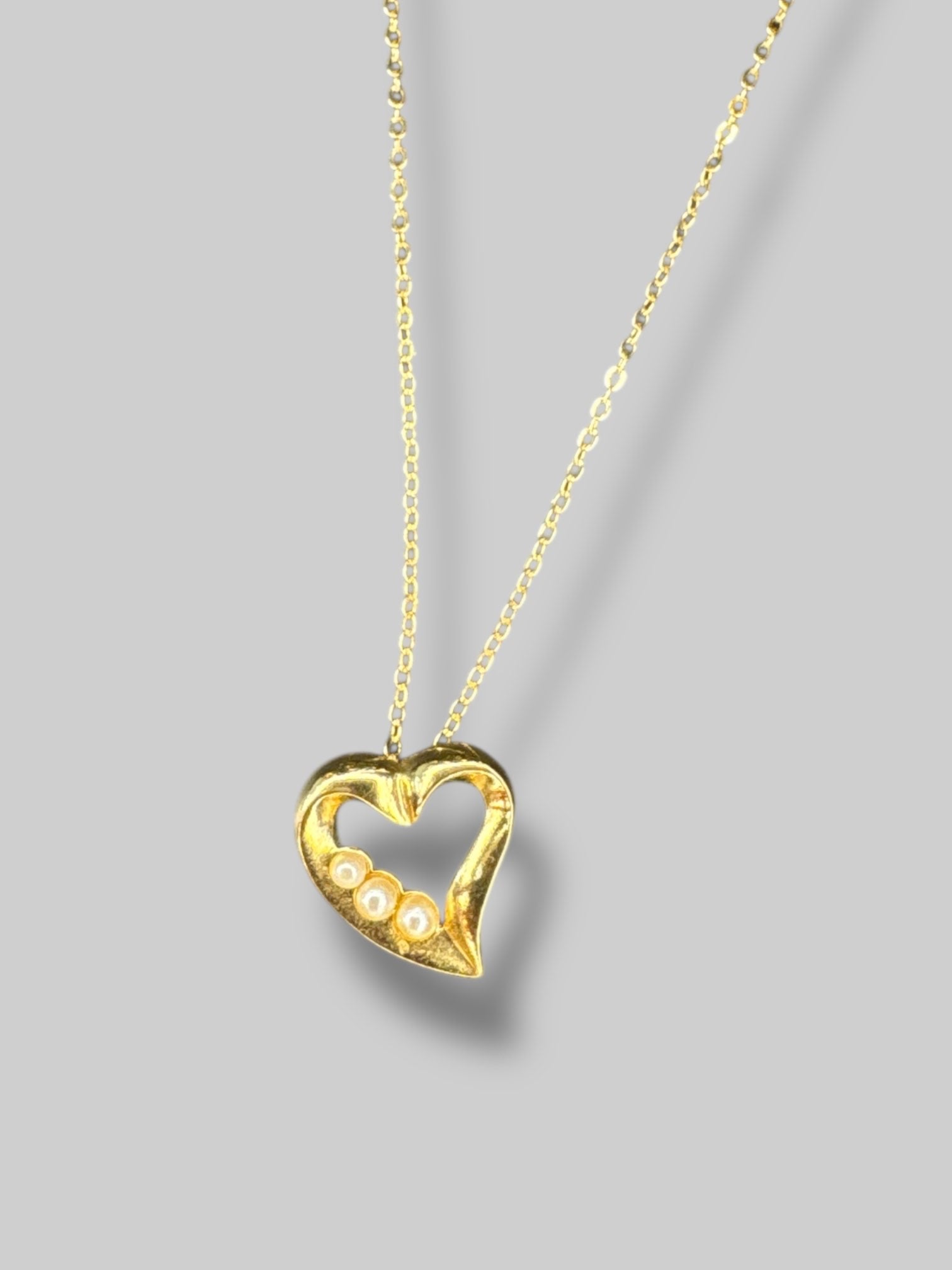 Gold tone, necklace with heart shape, pendant, and pearl details