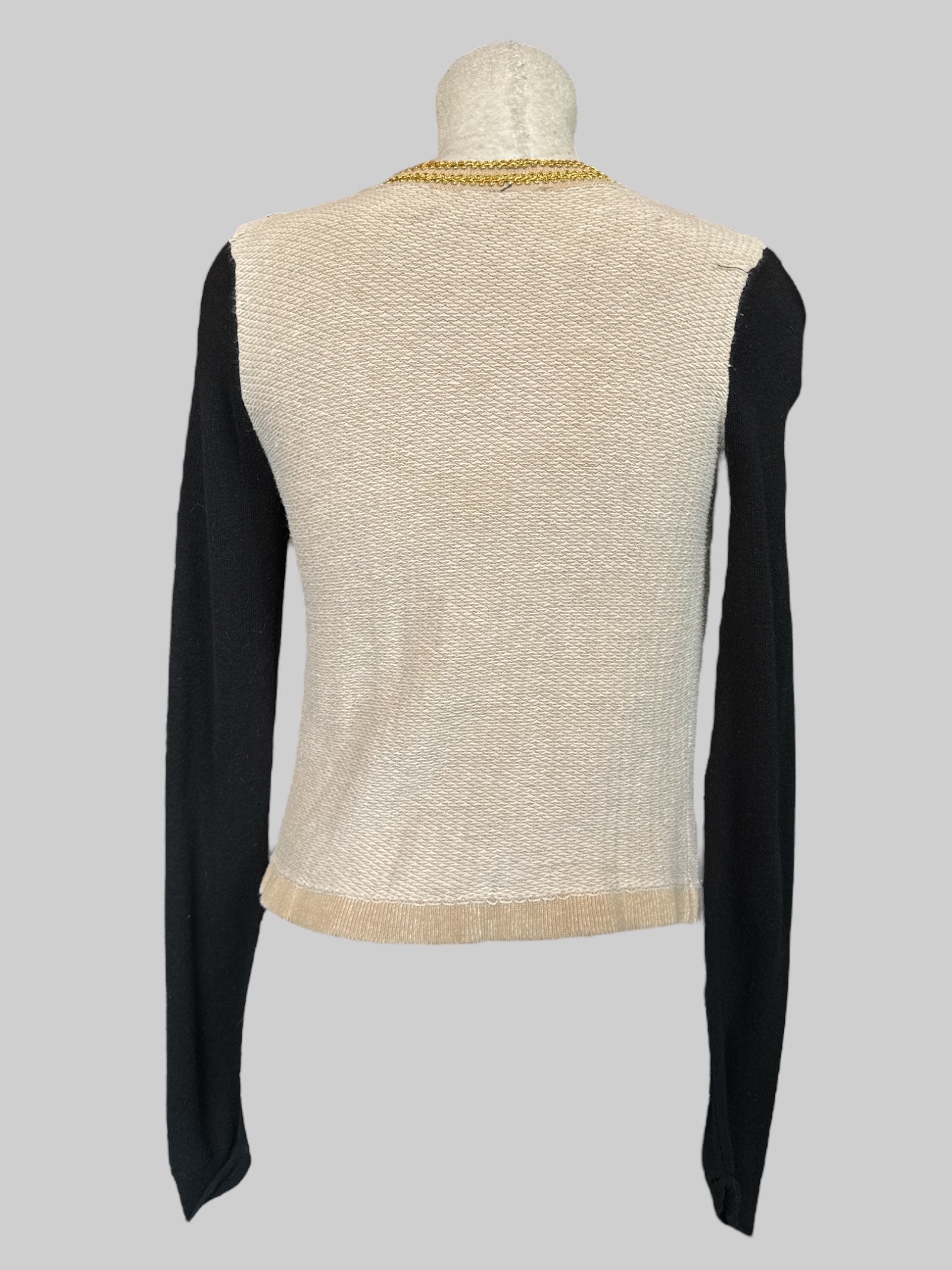 S cream cardigan with black sleeves, gold details, beads, and faux pockets