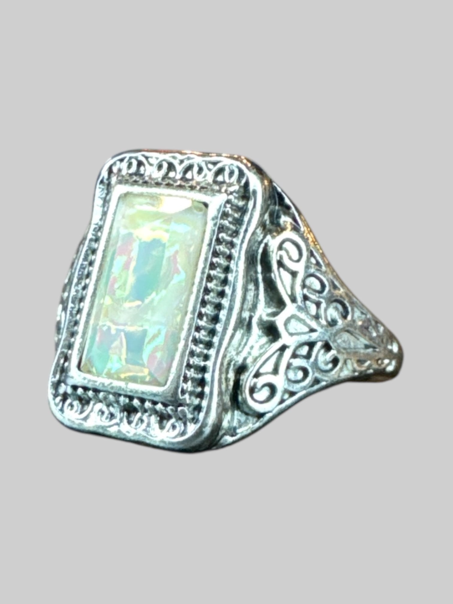 Size 7.5 Silver colored ring with designs on side with iridescent stone