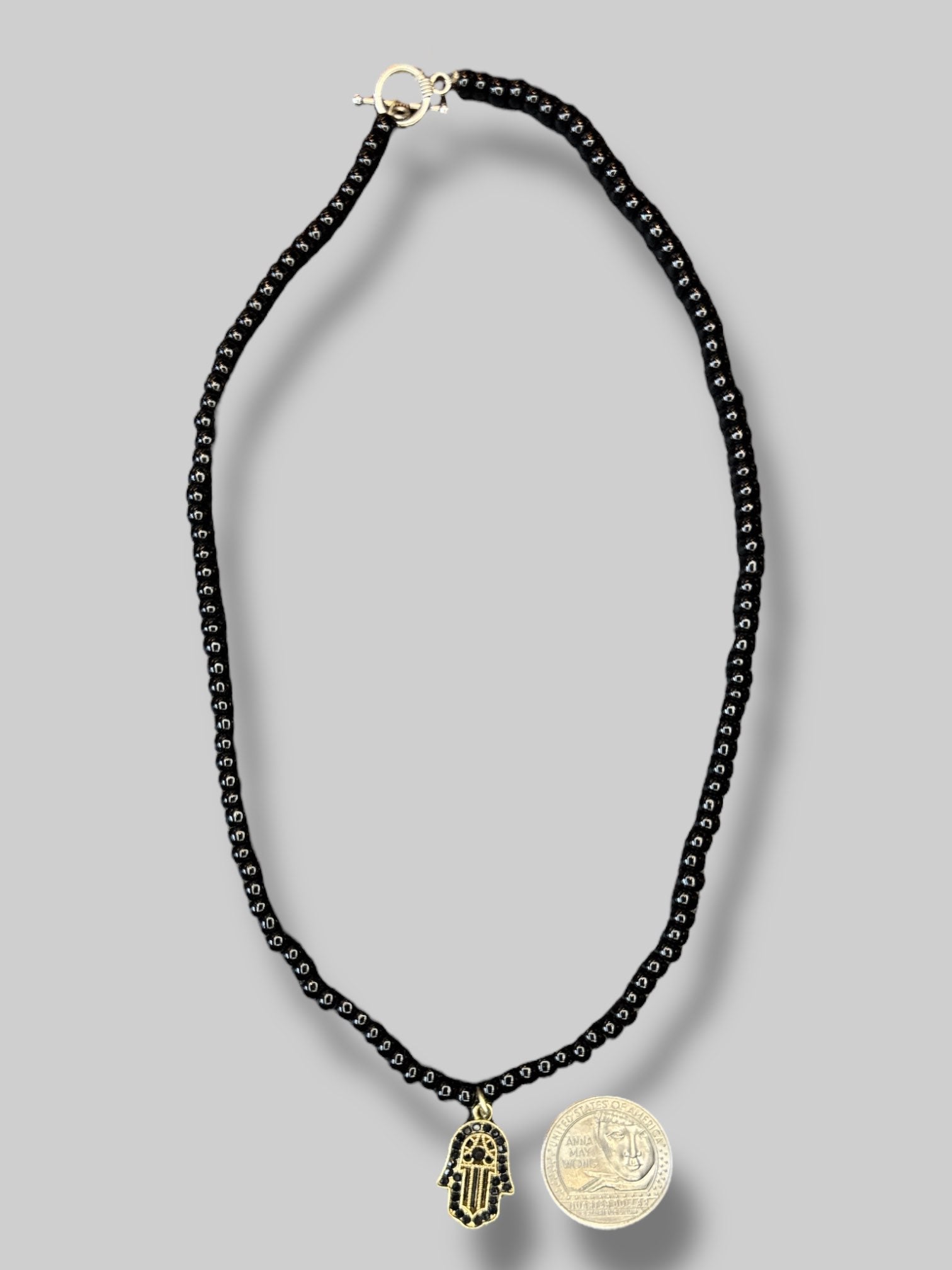 Black beaded necklace with hasma hand pendant