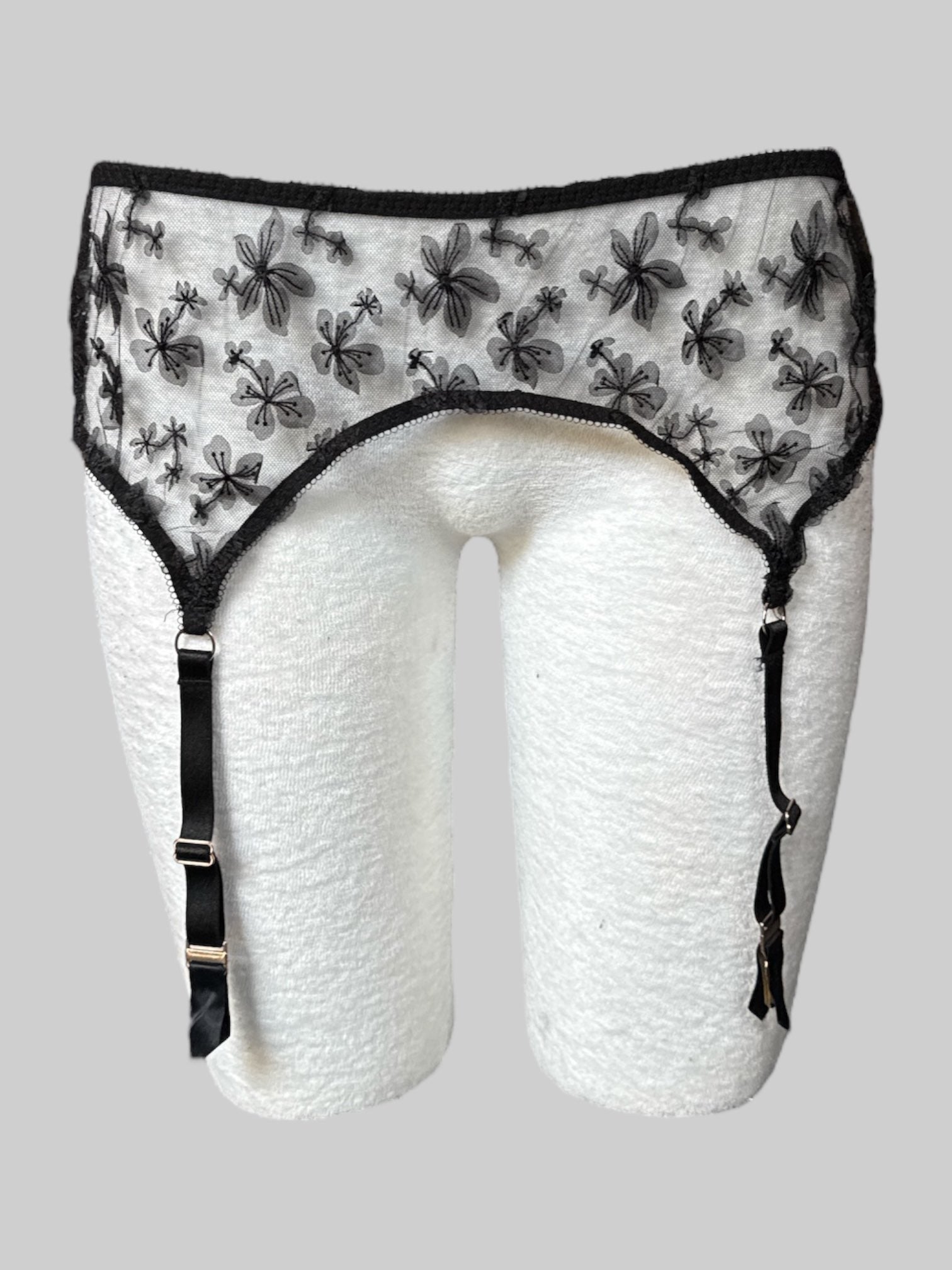 1X Black lacey garter belt with floral design and clasp closure on back