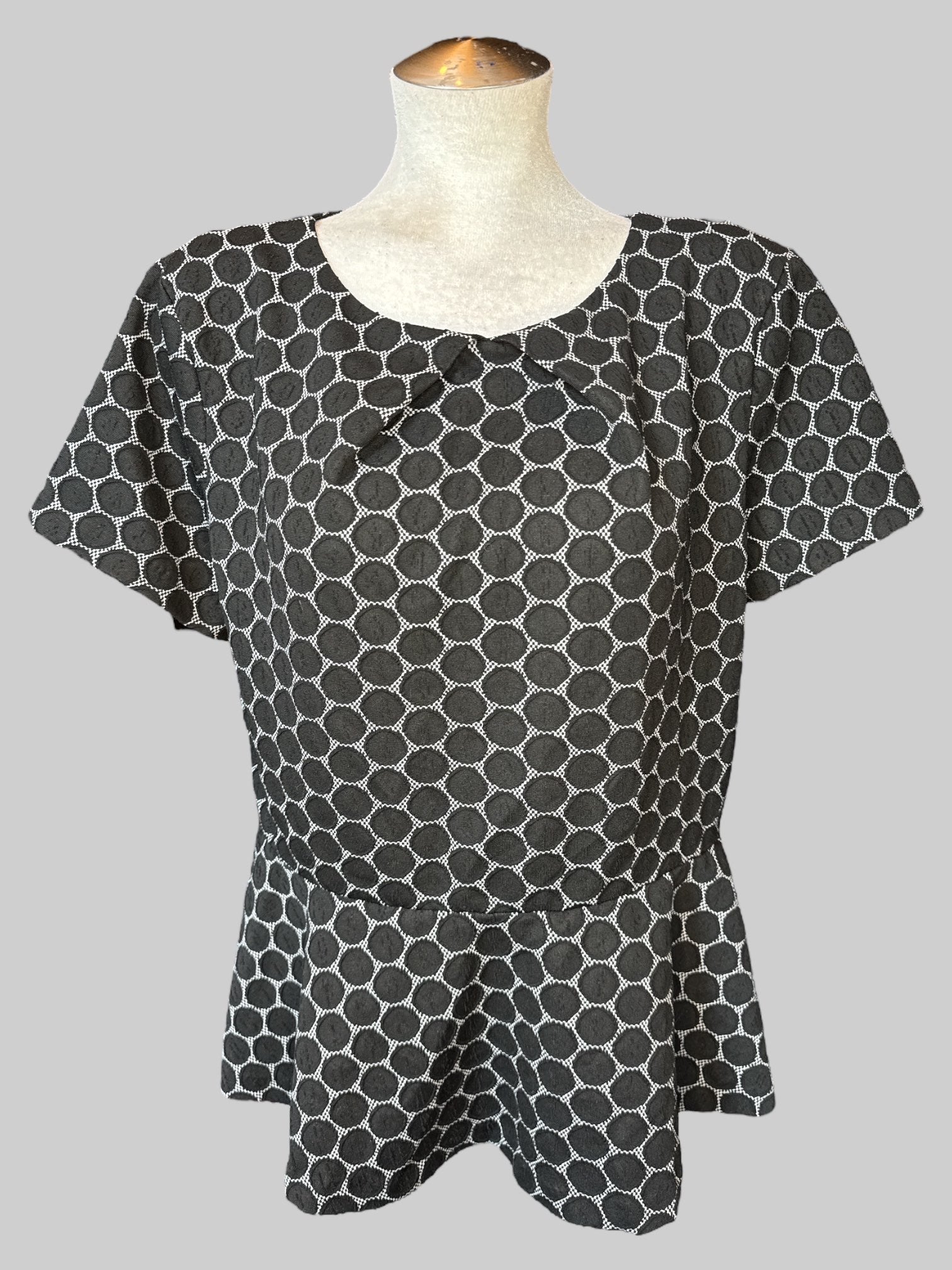 0X Black short sleeve peplum top with white and black dotted design, and keyhole and button on back