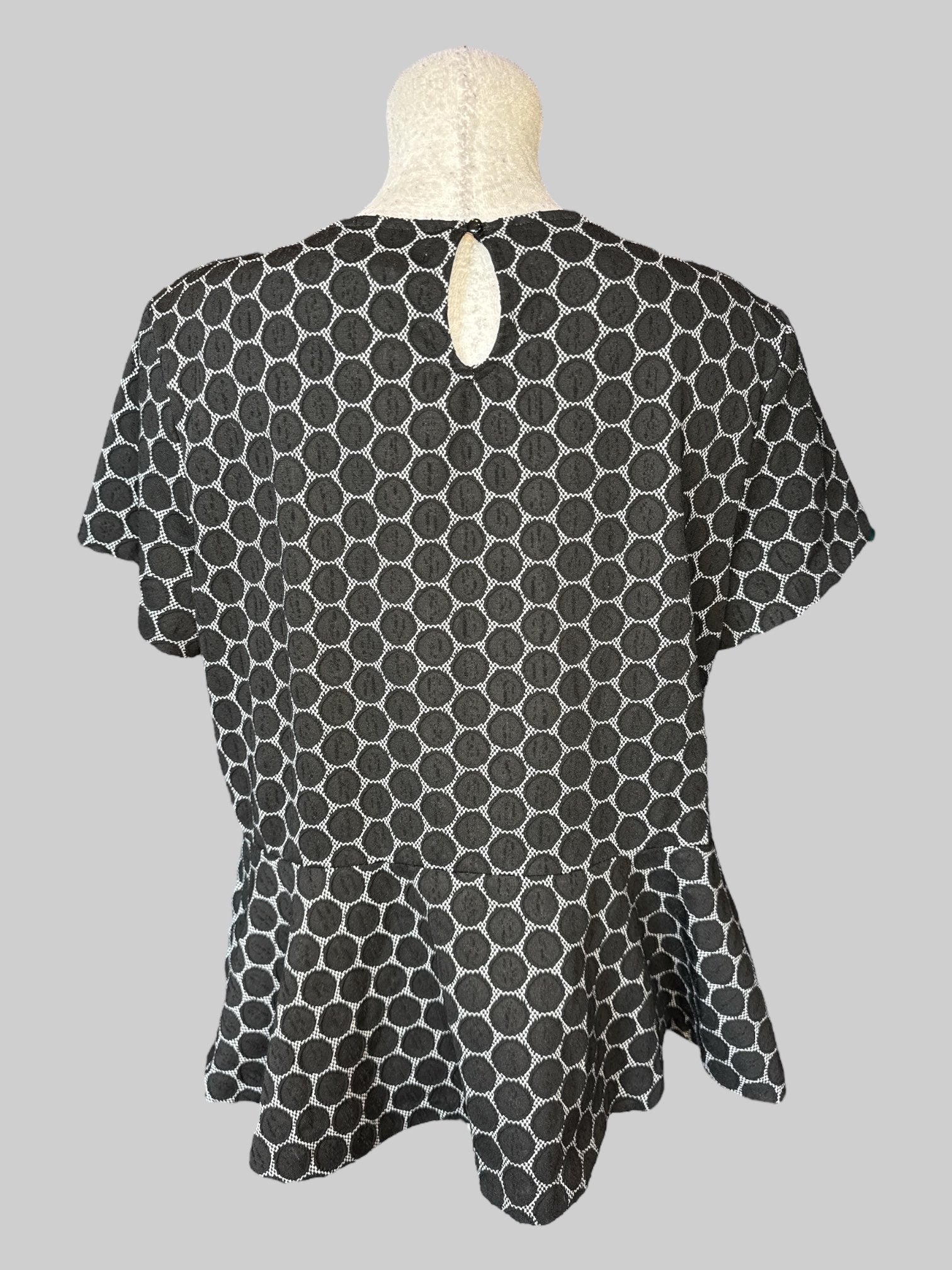 0X Black short sleeve peplum top with white and black dotted design, and keyhole and button on back
