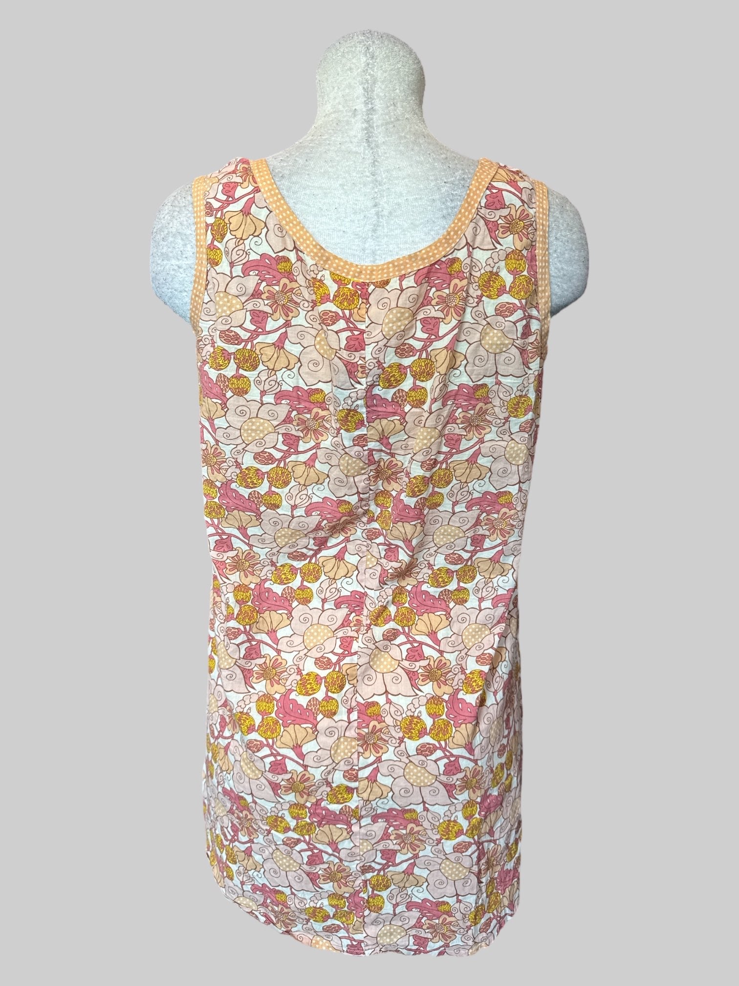 L Off-white sleeveless top with pink yellow and orange floral design, and pockets with buttons and ties on front