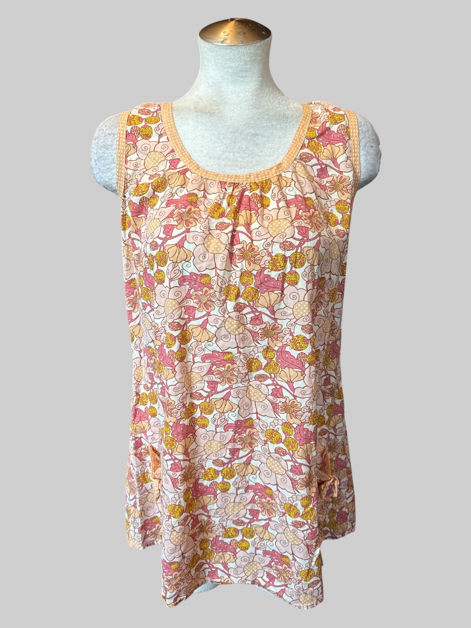L Off-white sleeveless top with pink yellow and orange floral design, and pockets with buttons and ties on front