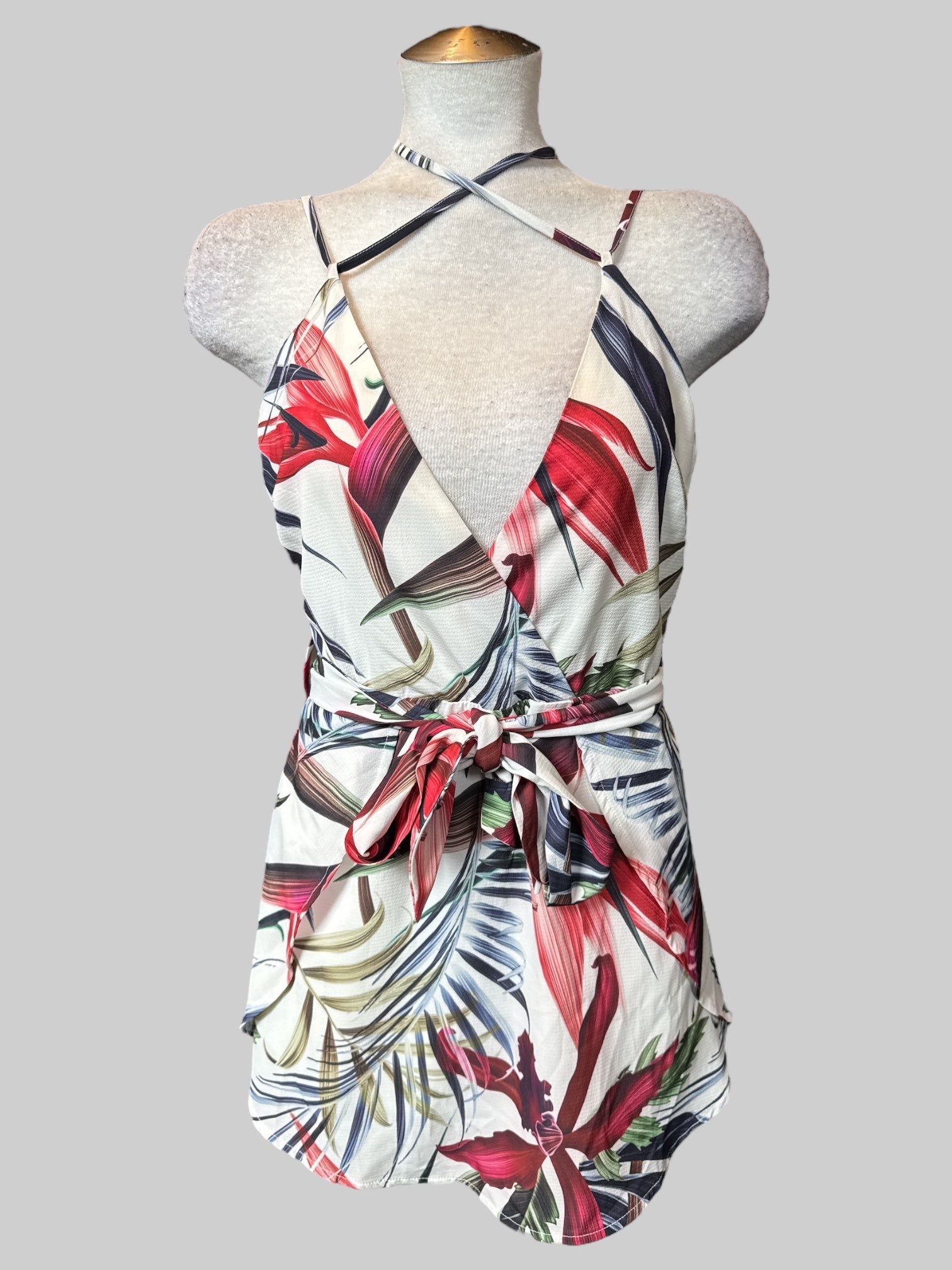 M White sleeveless floral romper with faux wrap design, tie belt, adjustable straps with tie, and zipper on back