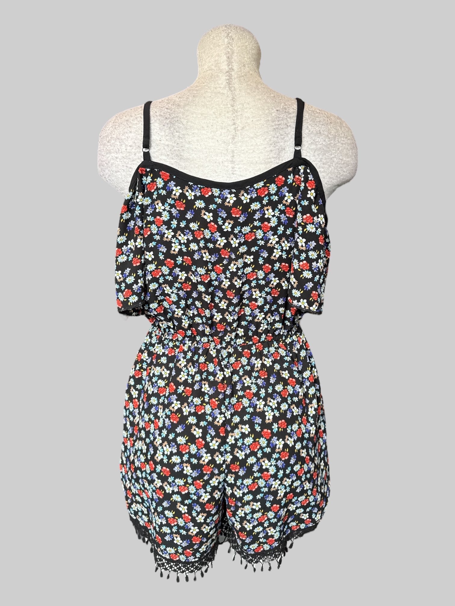 S Black floral romper with faux wrap design, faux tie on front, and tassels on the bottom