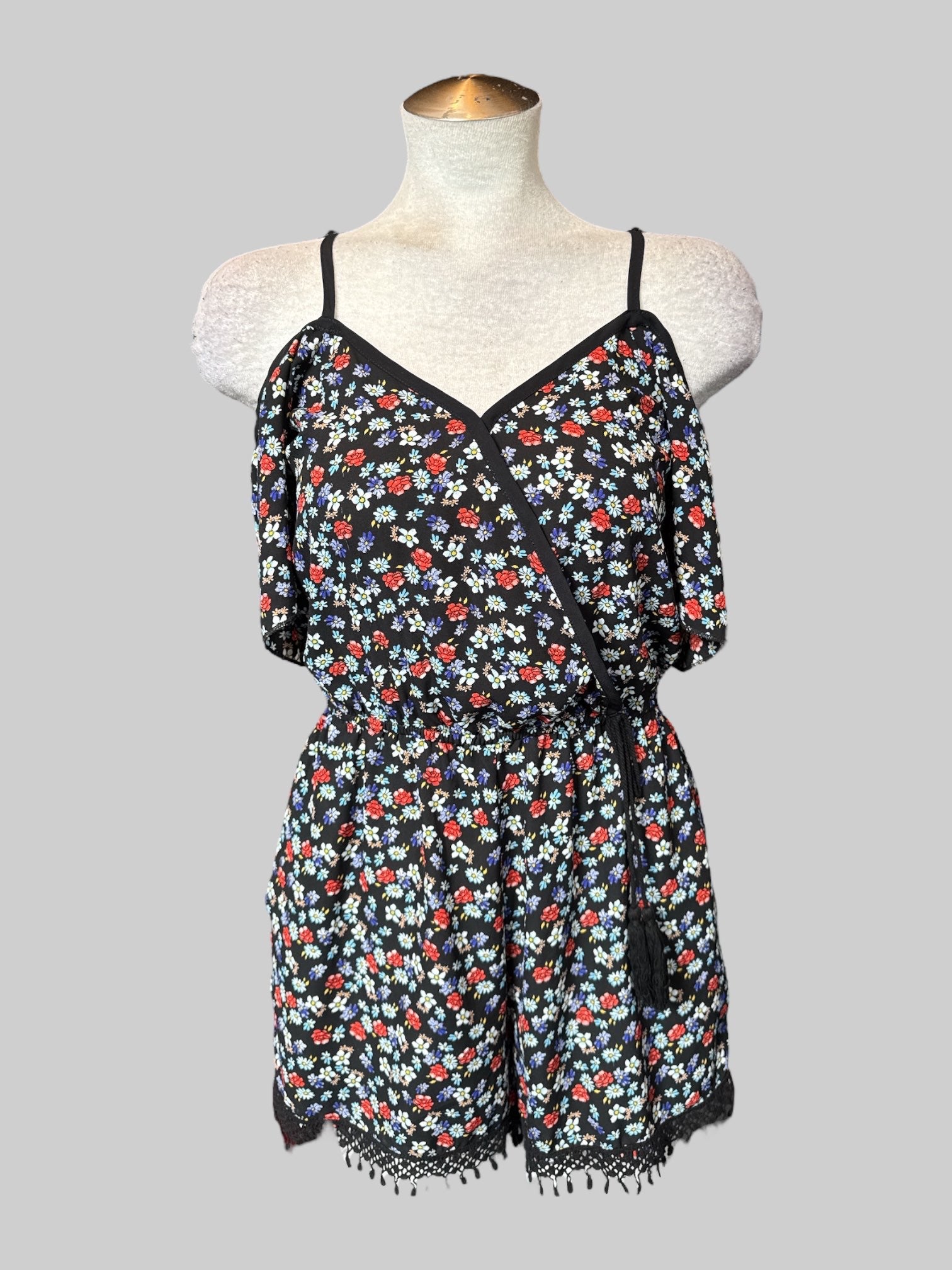 S Black floral romper with faux wrap design, faux tie on front, and tassels on the bottom