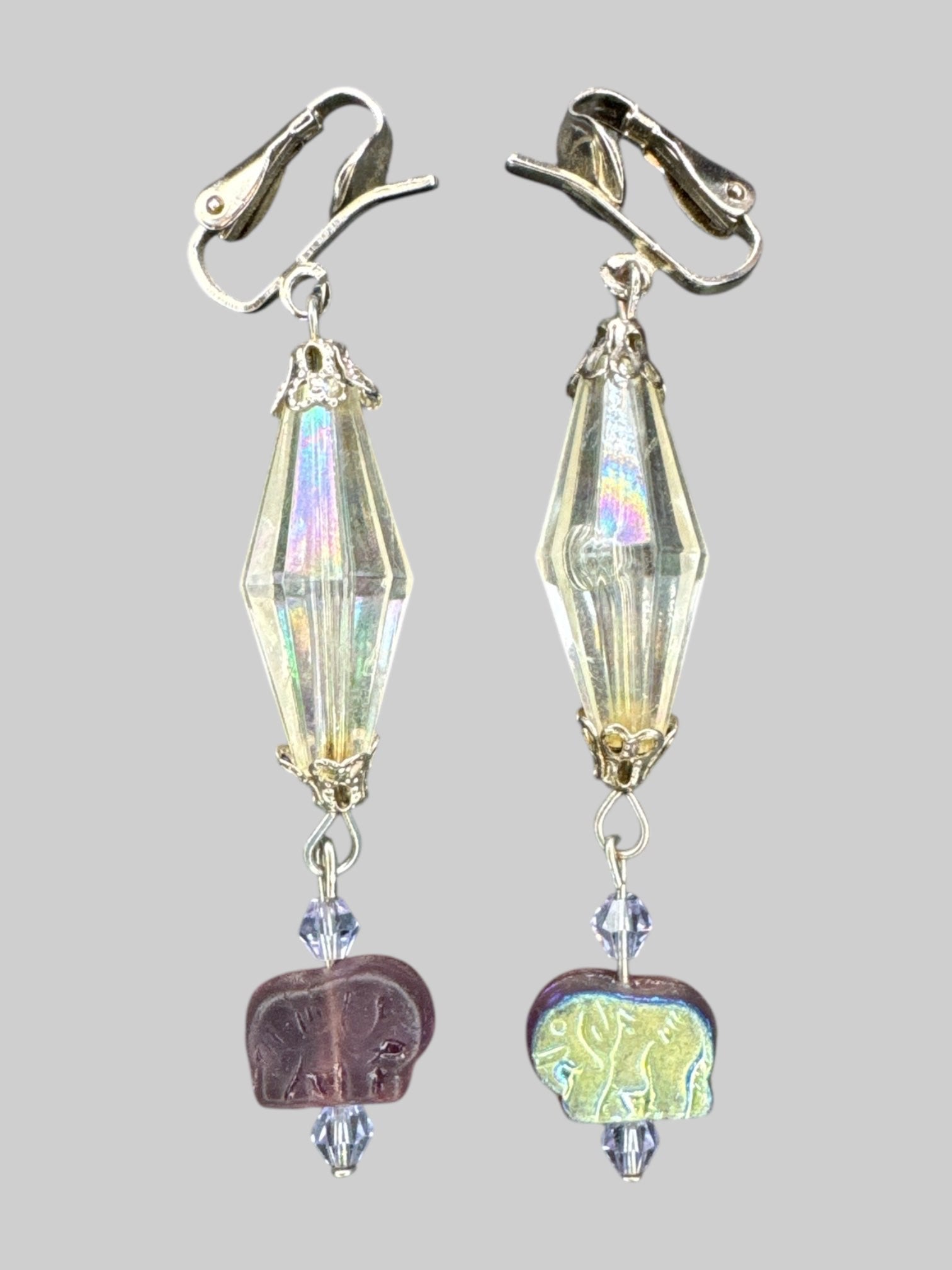 Silver tone dangly clip on earrings with larger iridescent clear gem, and purple and iridescent elephants