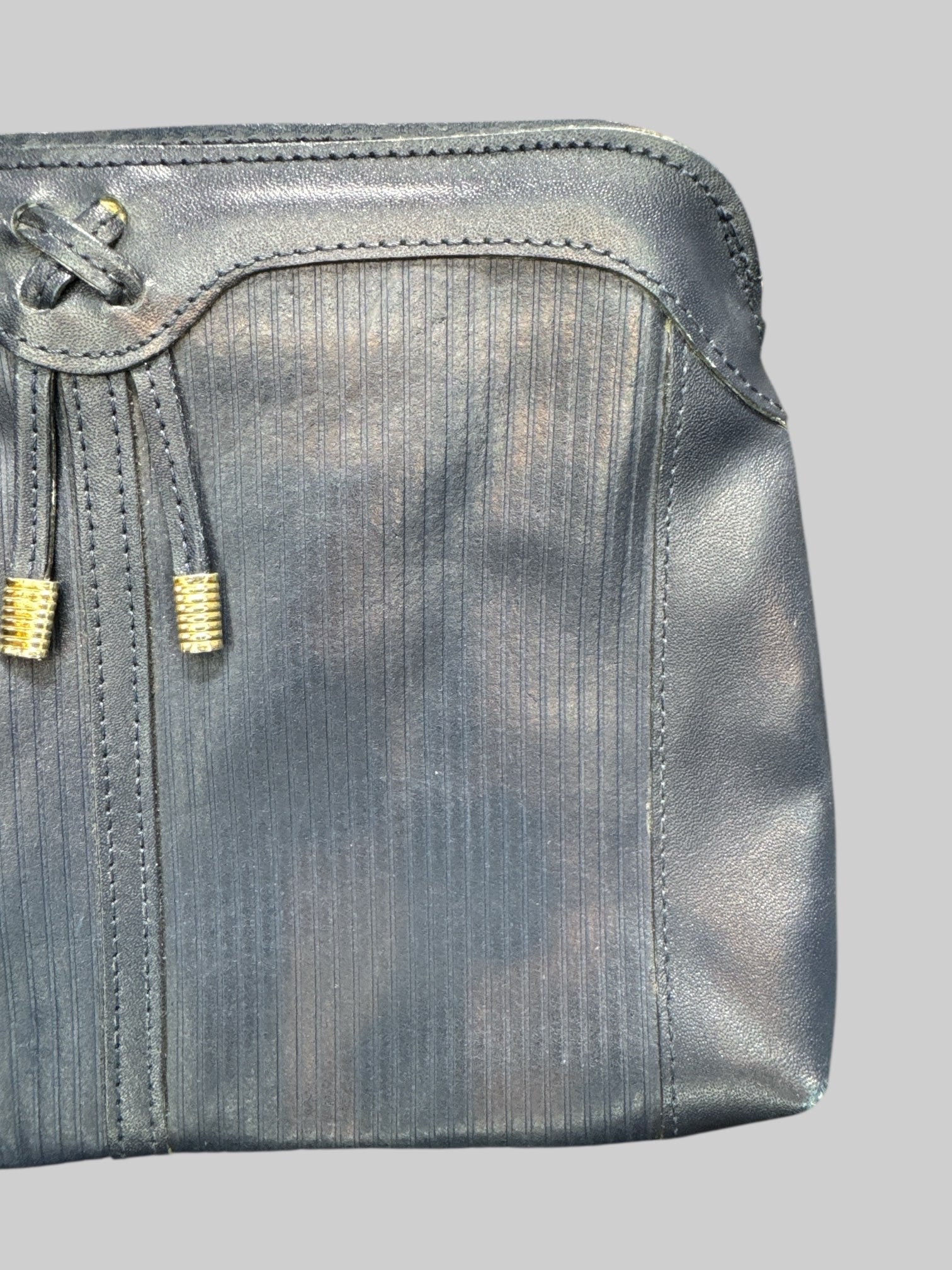 Blue leather handbag with faux drawstring on front, multiple zipper pockets, and hooks for shoulder strap