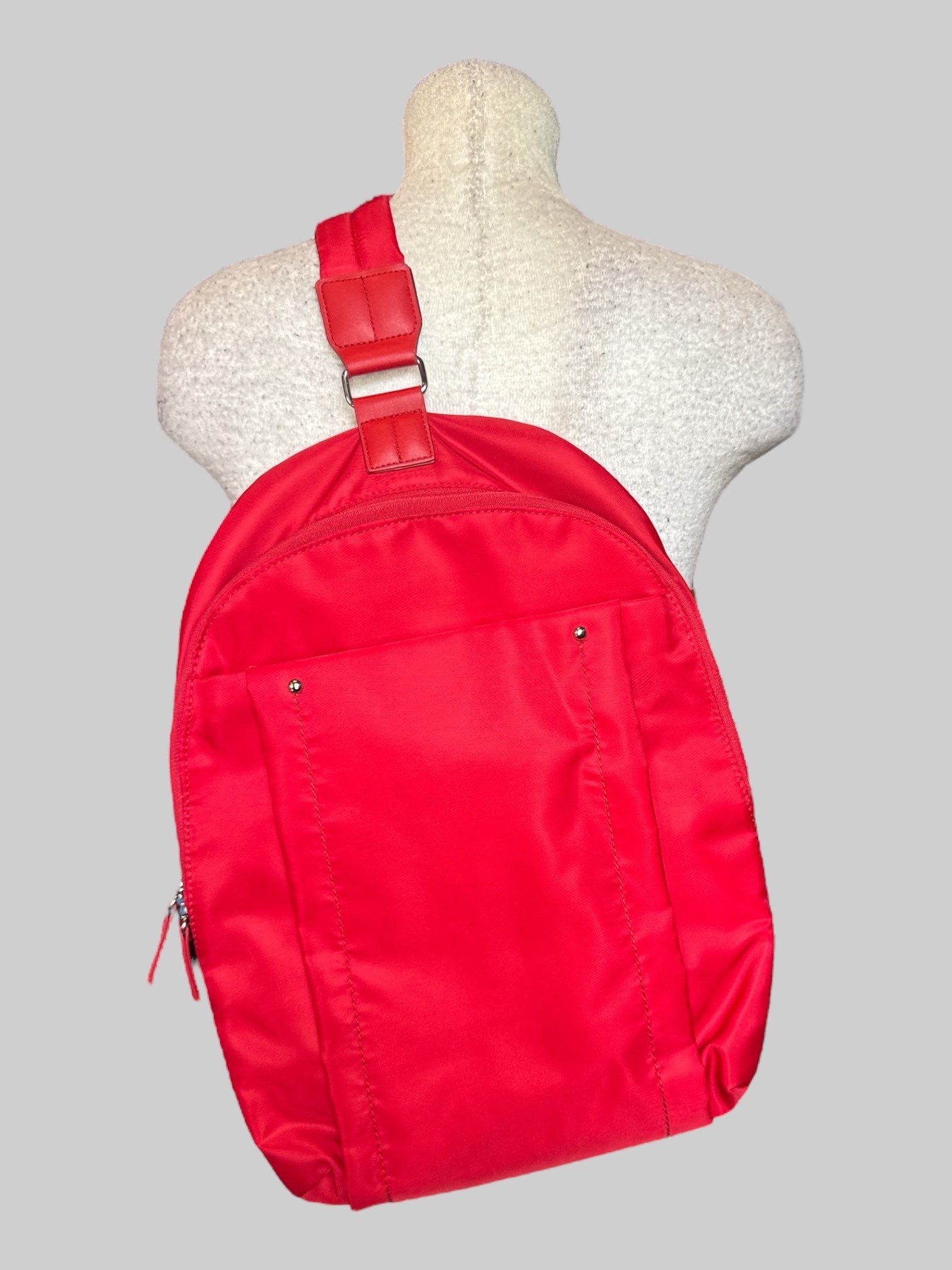Red small backpack with one shoulder strap, and multiple pockets inside and out