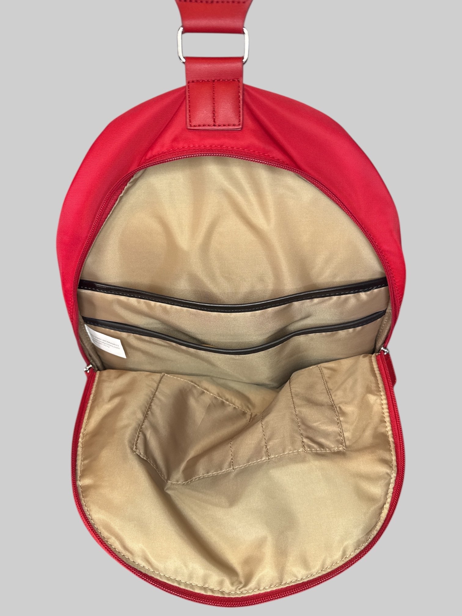Red small backpack with one shoulder strap, and multiple pockets inside and out