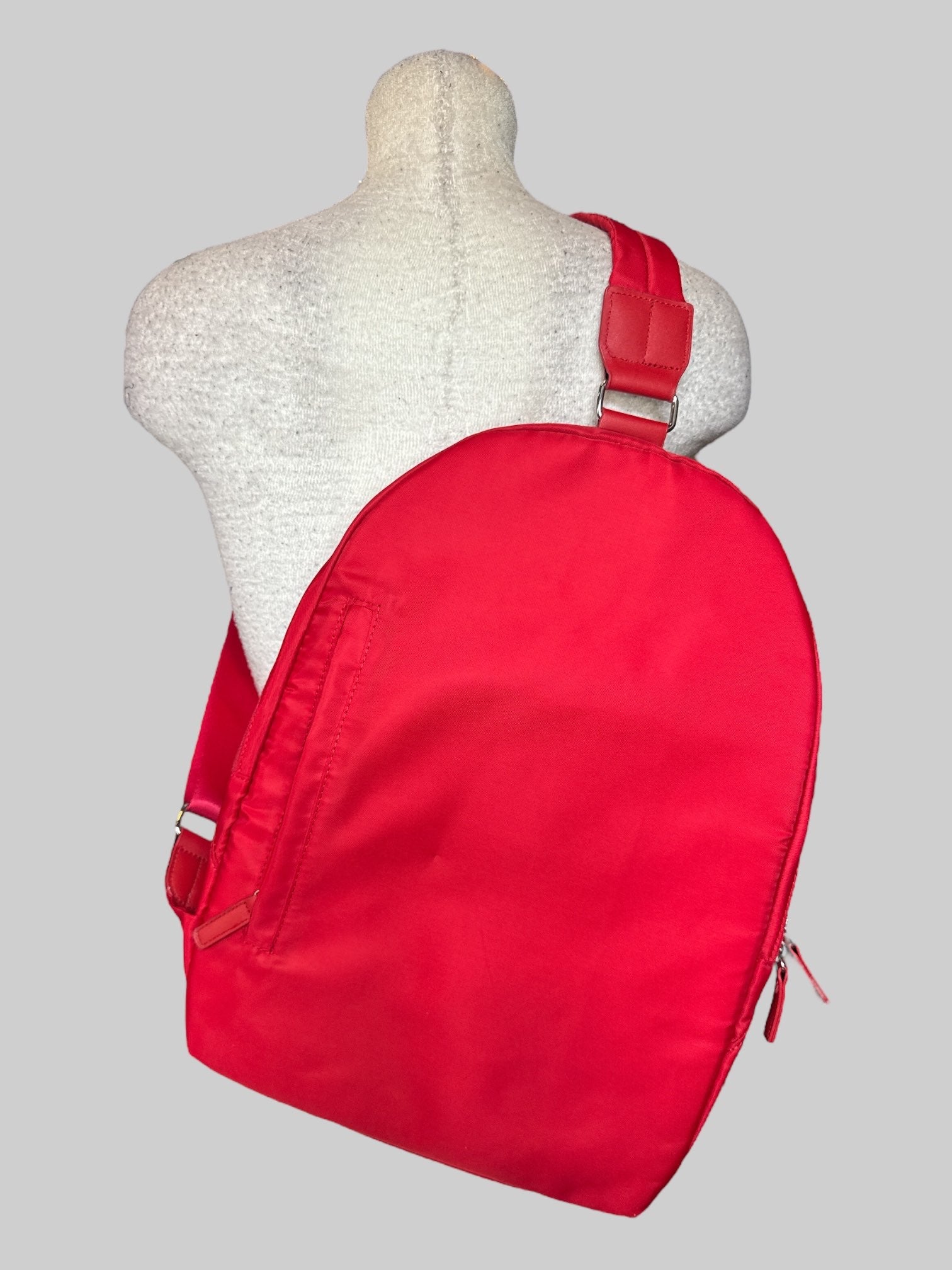 Red small backpack with one shoulder strap, and multiple pockets inside and out