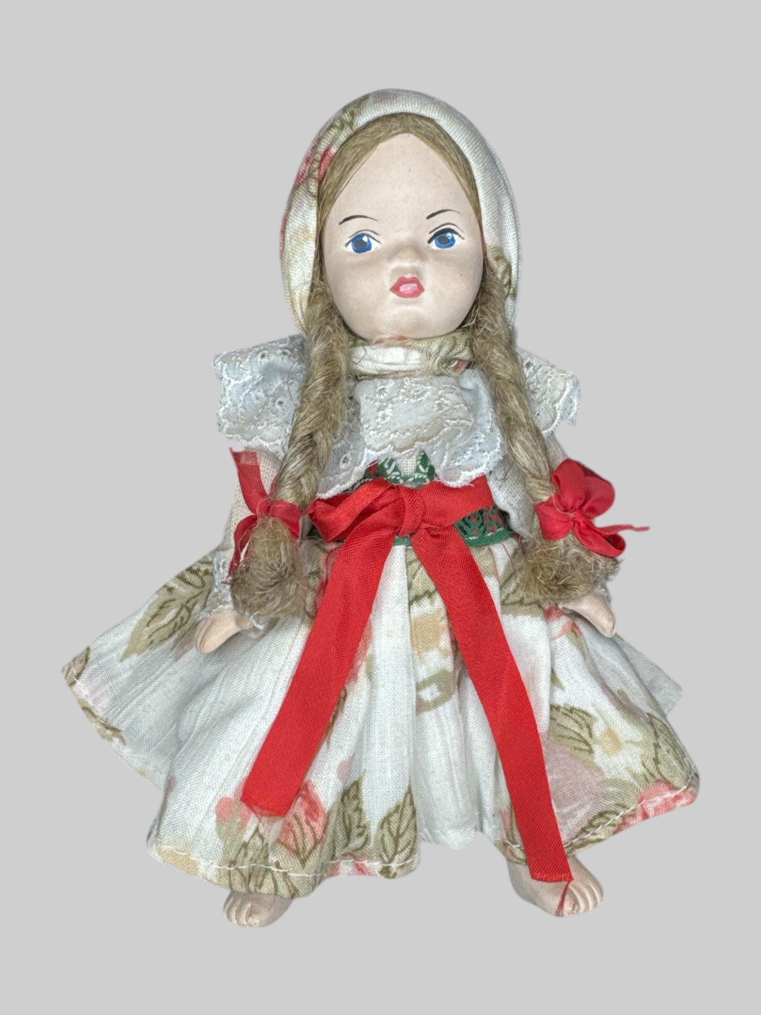 Small porcelain doll with floral clothing and red bows