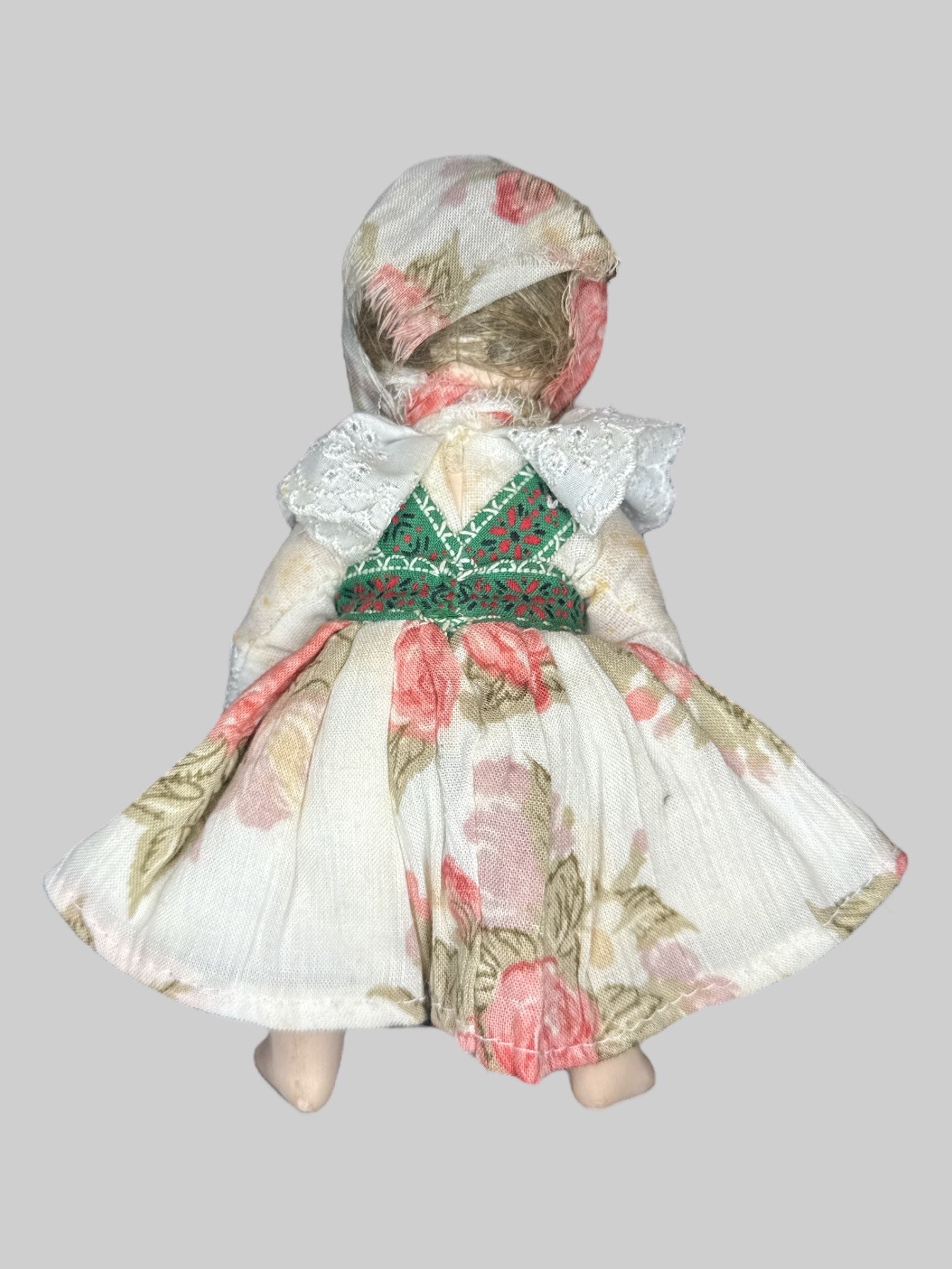 Small porcelain doll with floral clothing and red bows