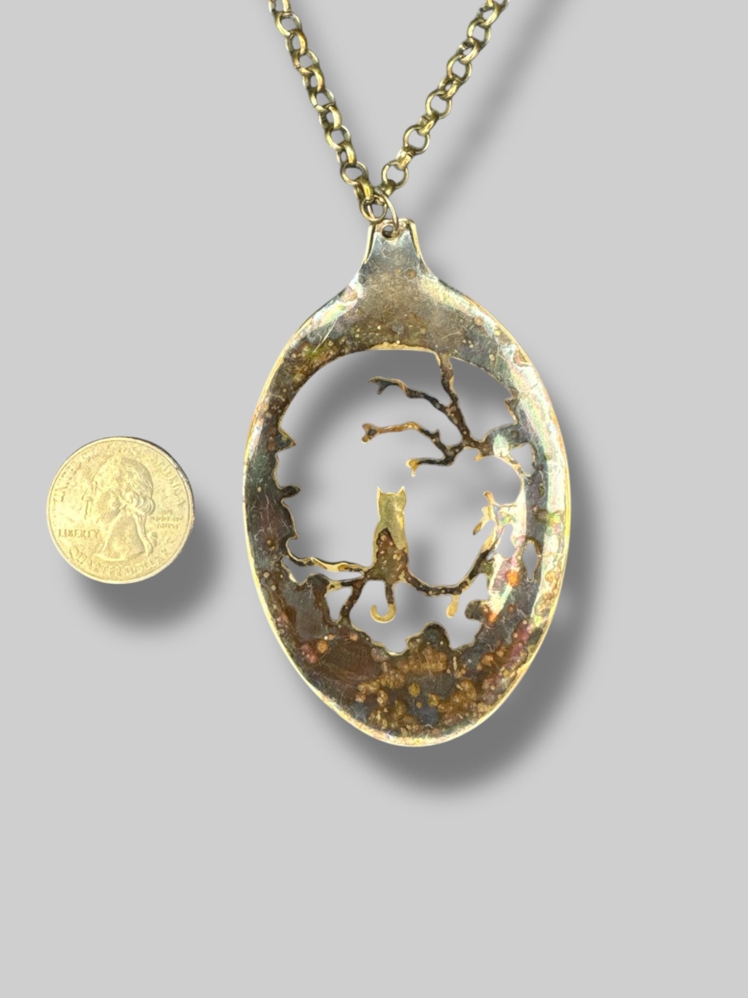 Gold tone necklace with cat and tree scene pendant