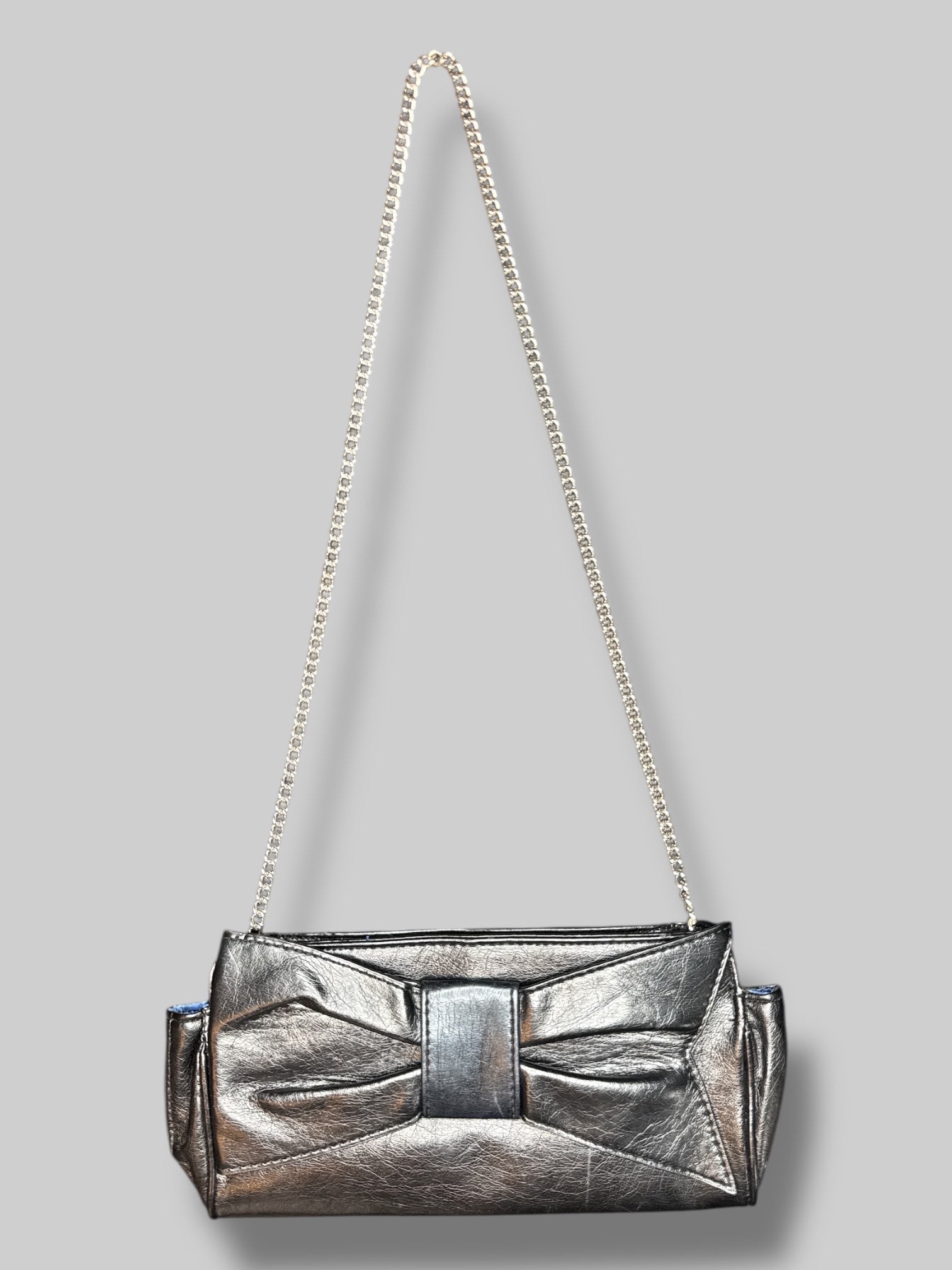 Vintage black leather purse, with chain, shoulder strap, snap button closure, and decorative bow on outside