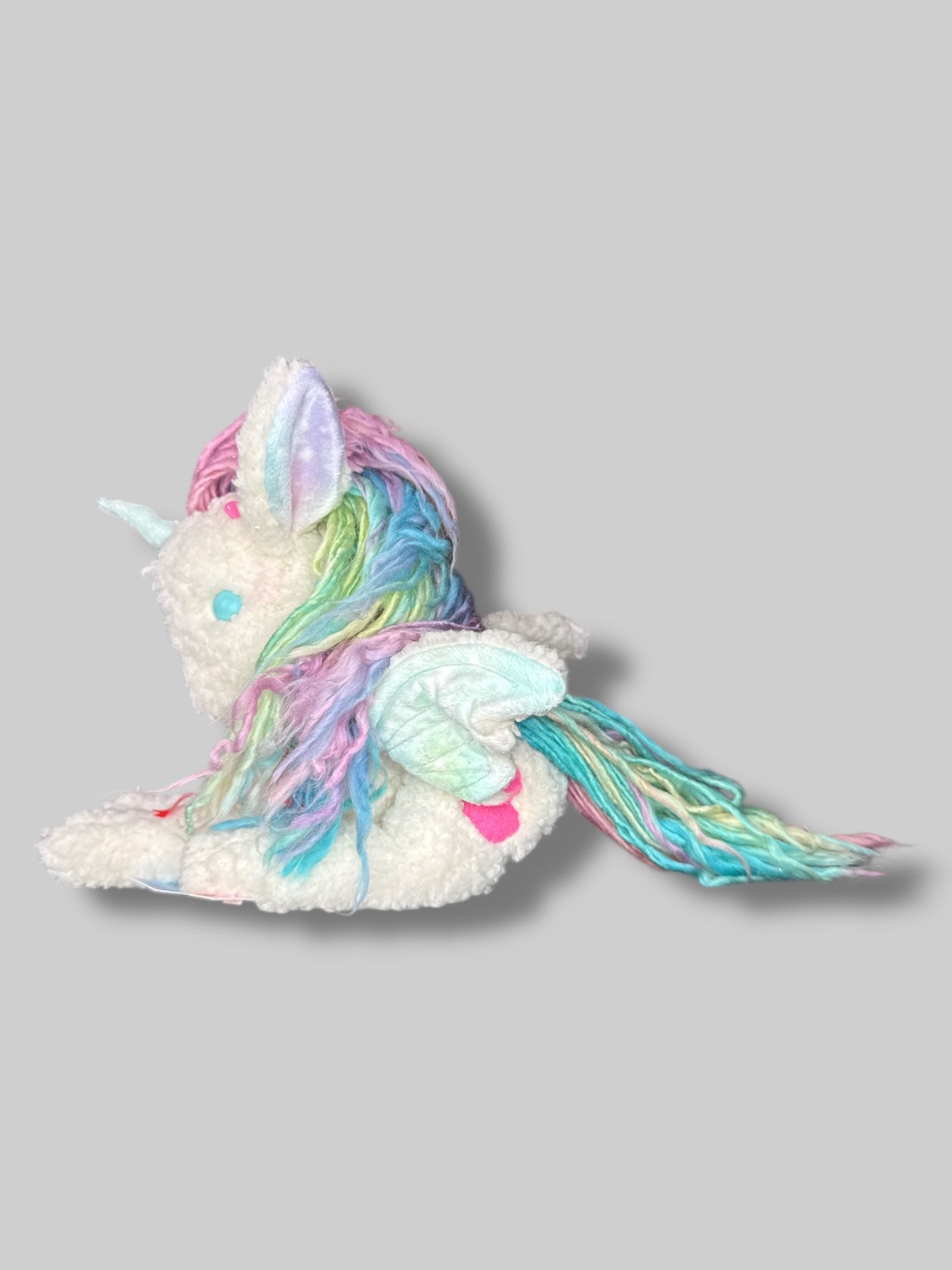 White fluffy unicorn plush with rainbow hair, and wings