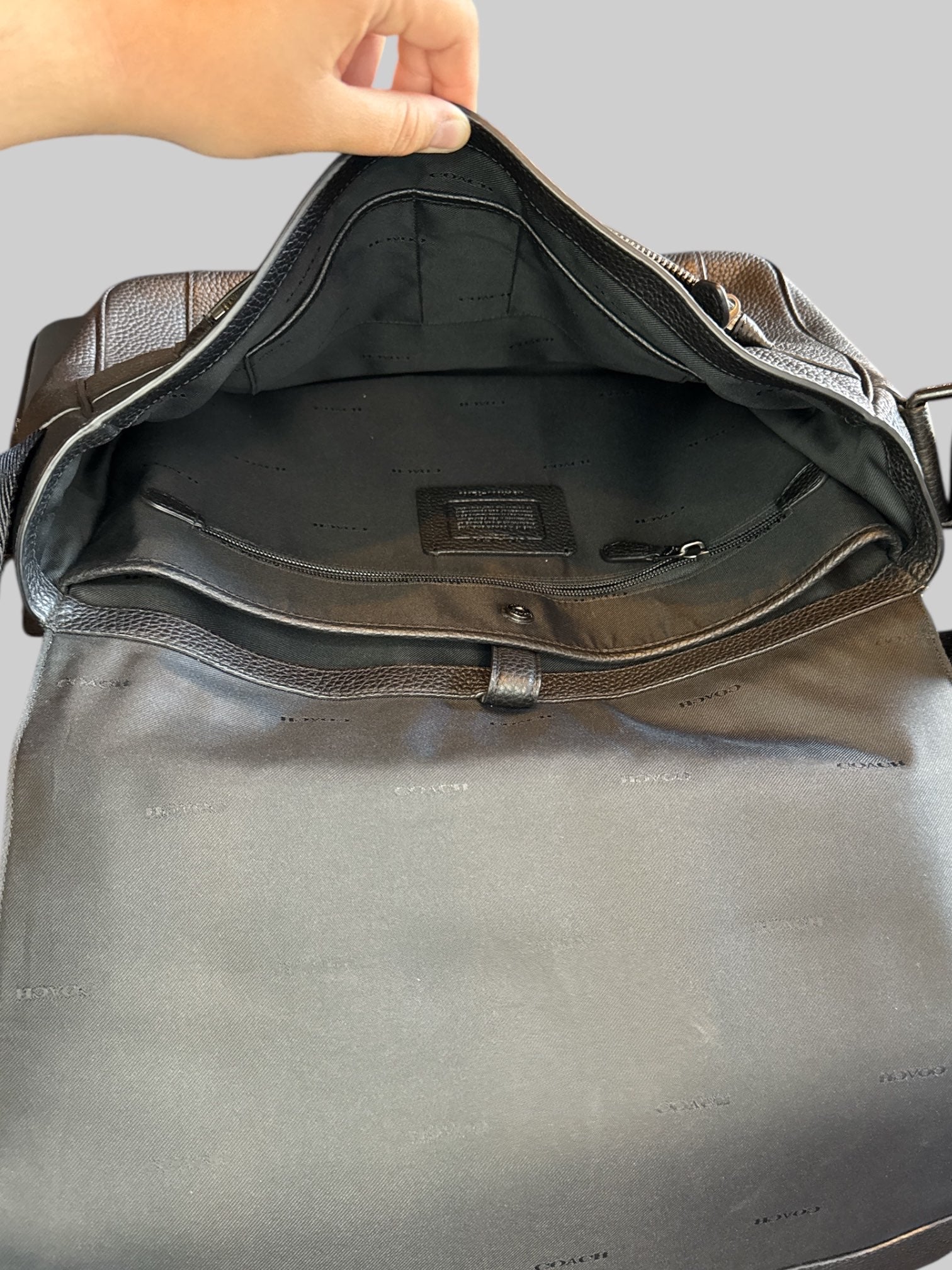 Genuine leather Coach laptop bag with multiple pockets inside, magnetic snap flap, and adjustable shoulder strap