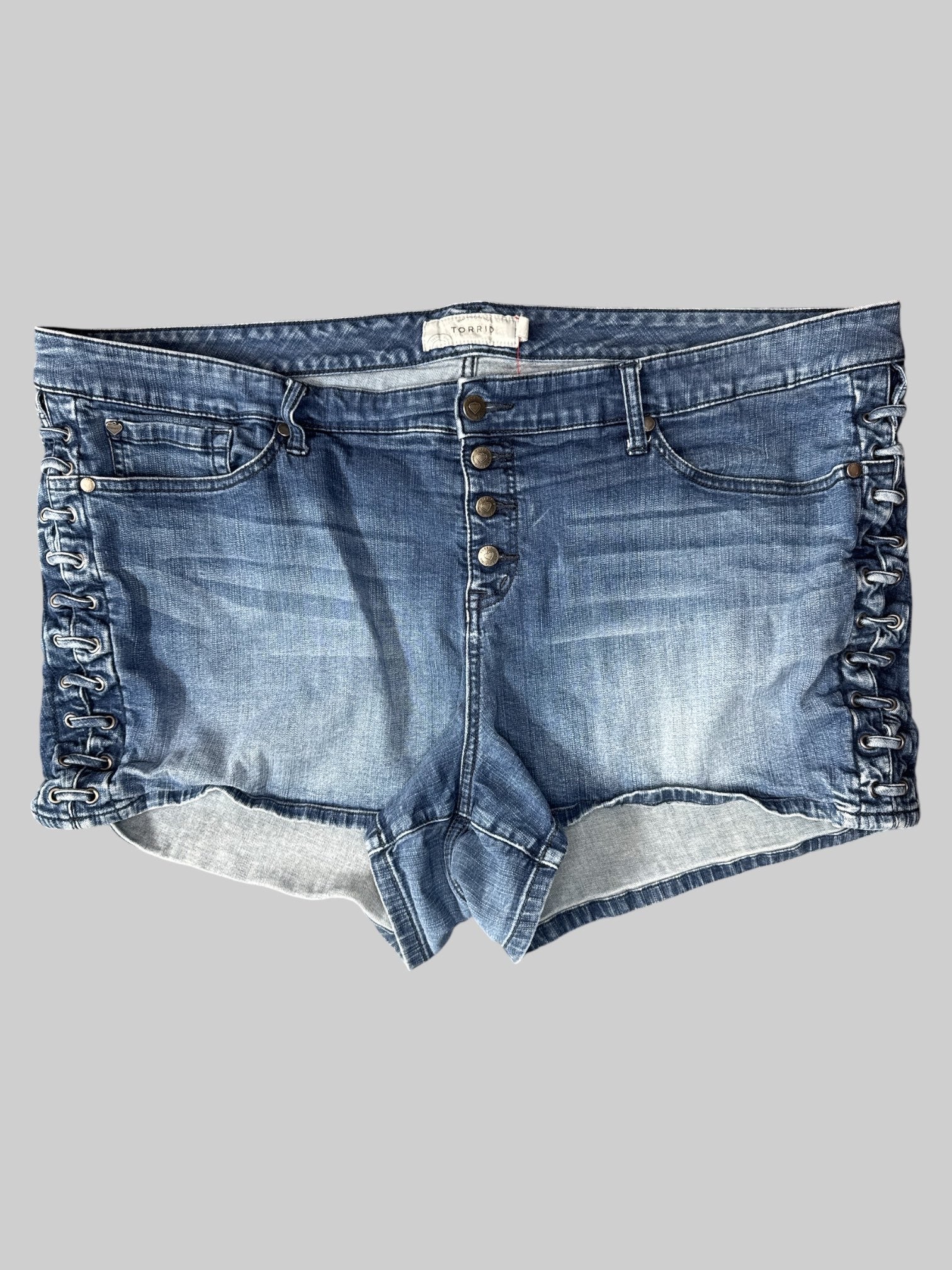 3X Blue denim shorts with multi button closure, pockets, belt, loops, and decorative lacing on sides