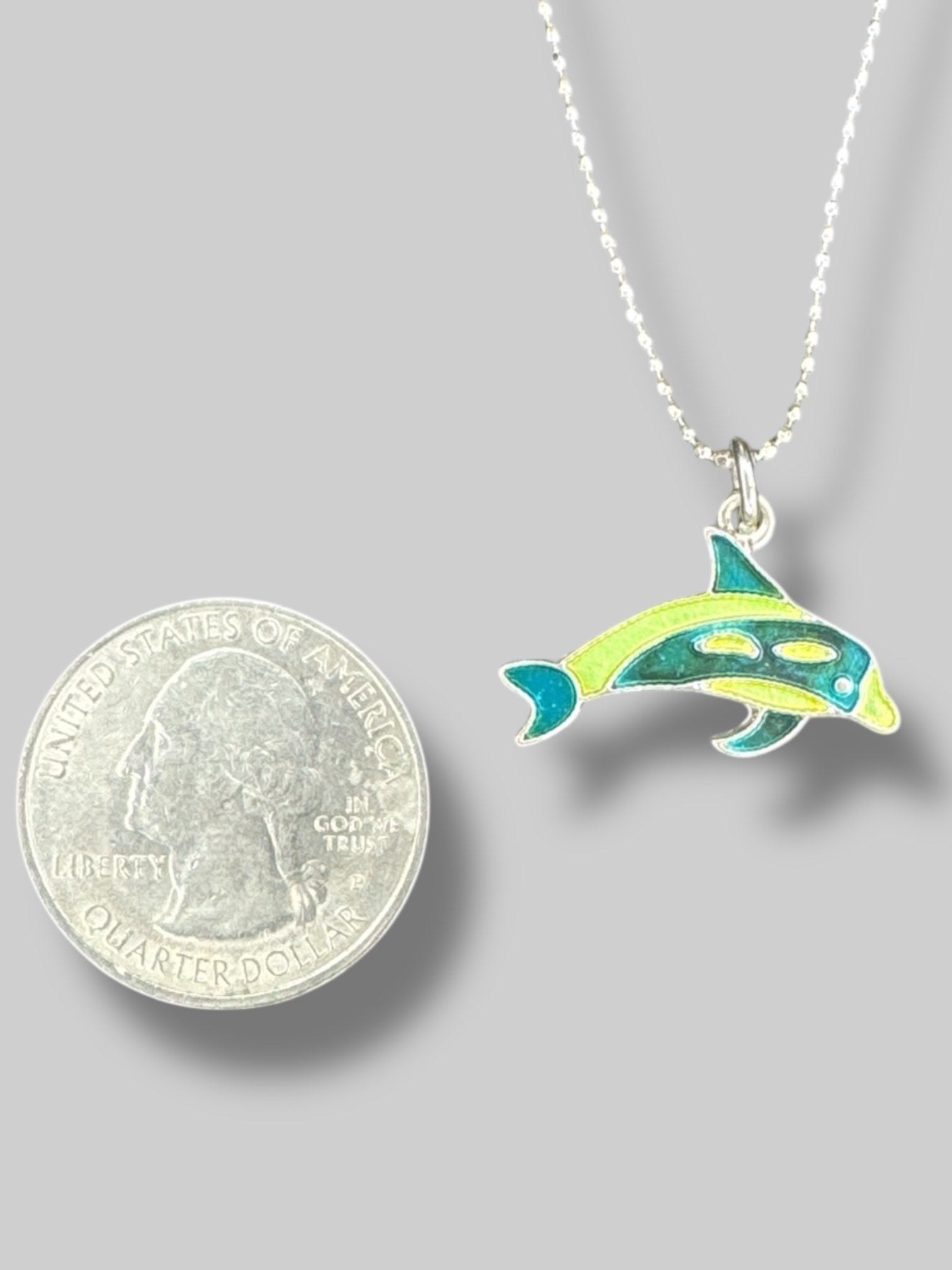 Silver colored necklace with green and blue dolphin pendant