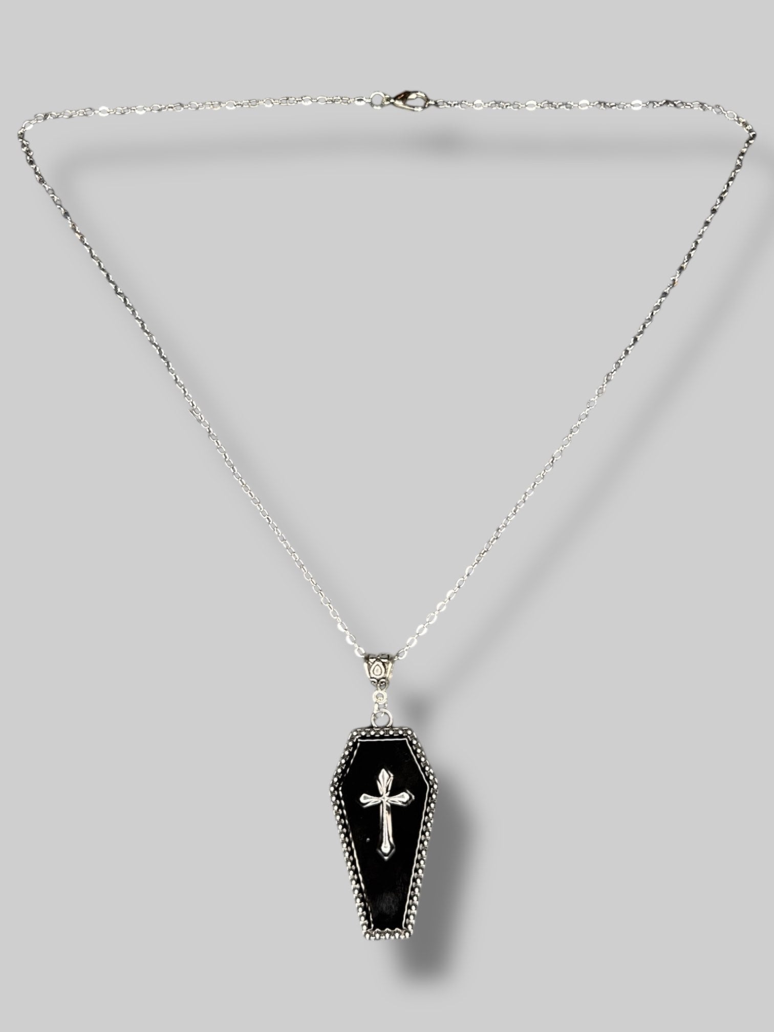 Silver tone necklace with black coffin pendant