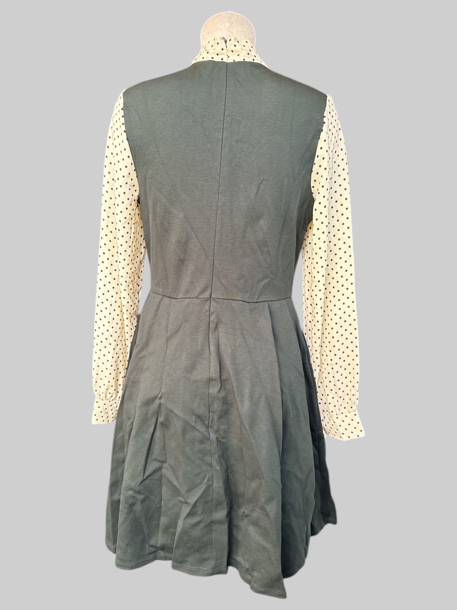 L Dark green dress with pleating, cream color sleeves with black polka dots, and tie