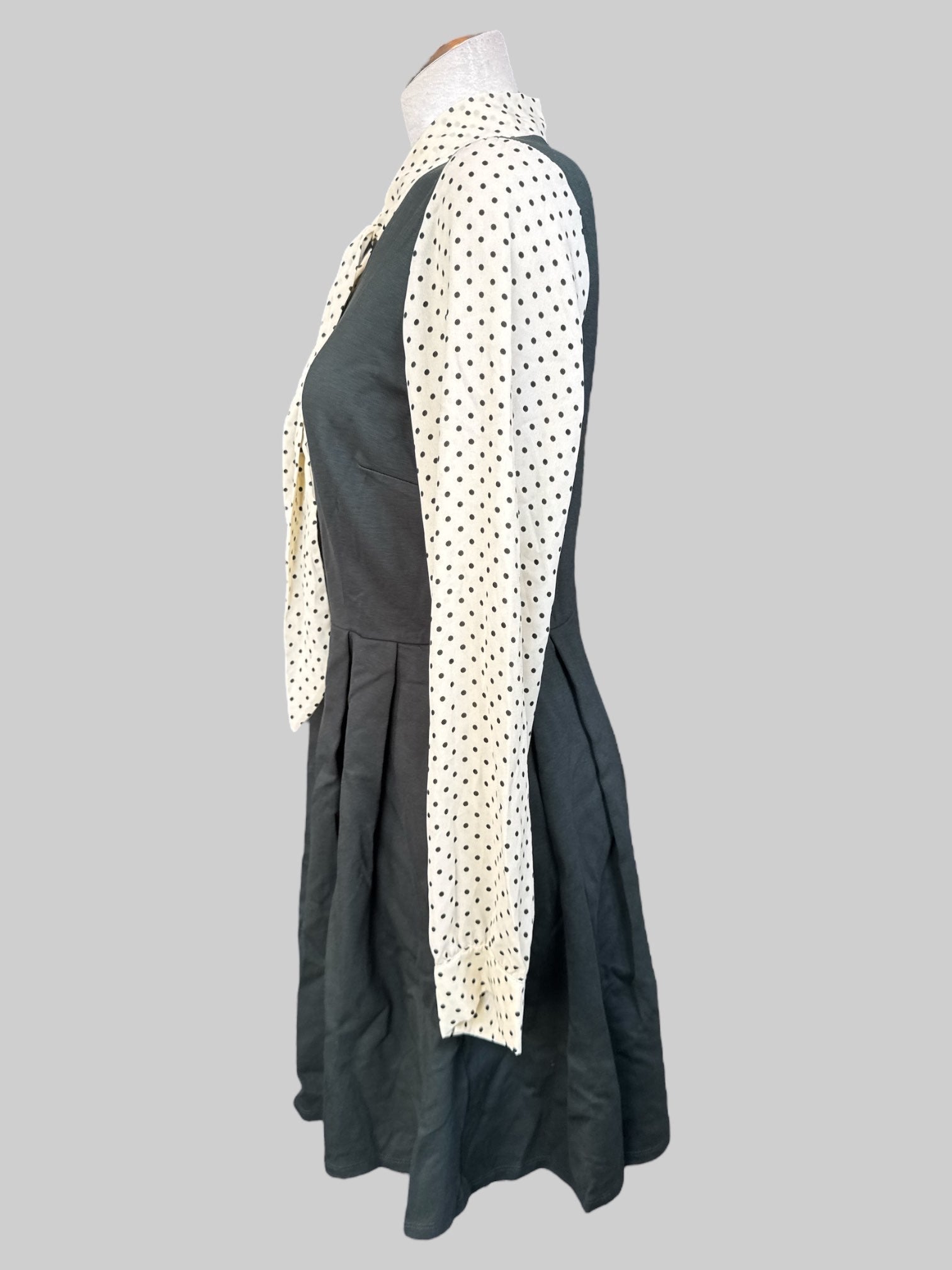 L Dark green dress with pleating, cream color sleeves with black polka dots, and tie