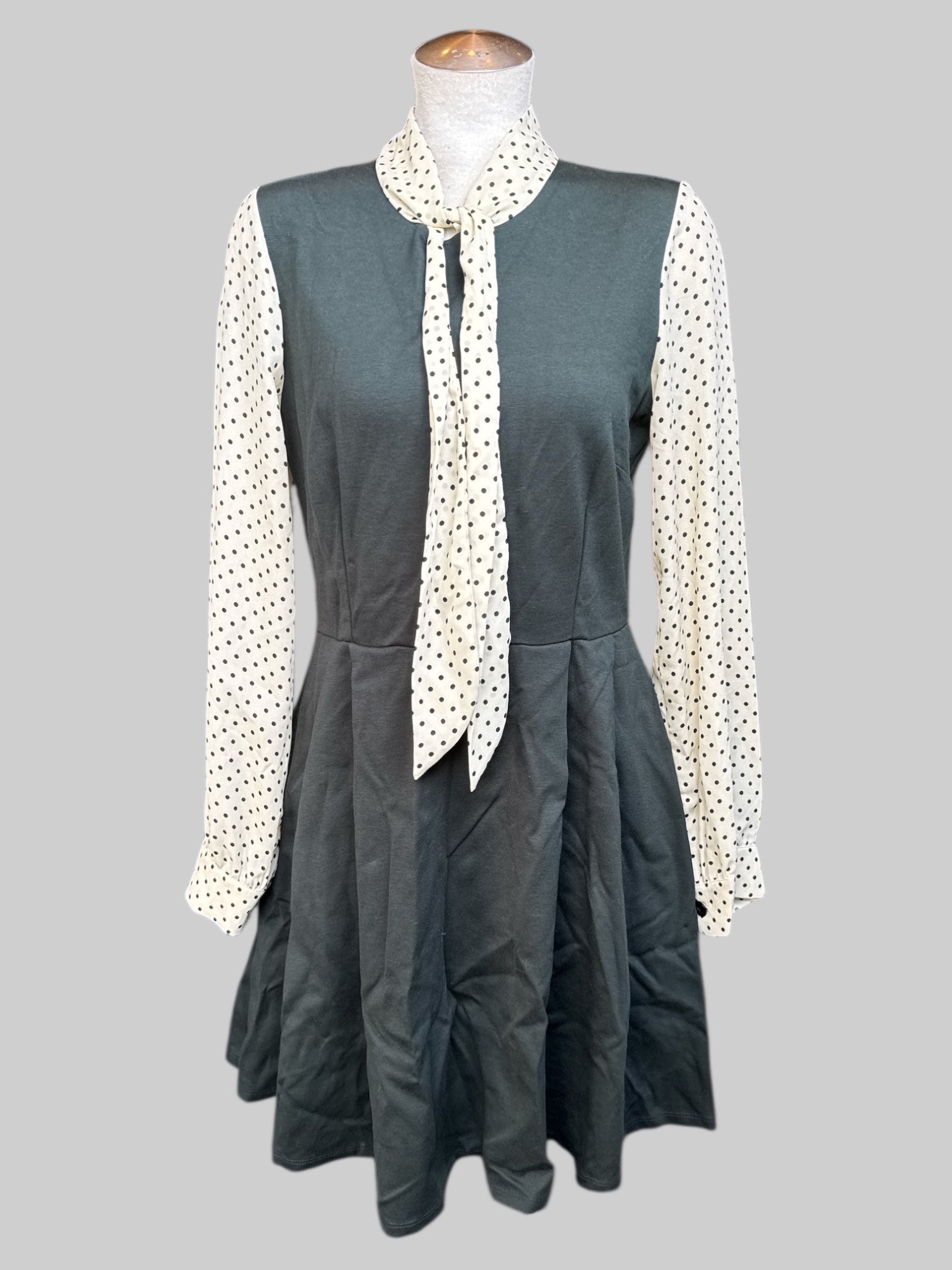 L Dark green dress with pleating, cream color sleeves with black polka dots, and tie