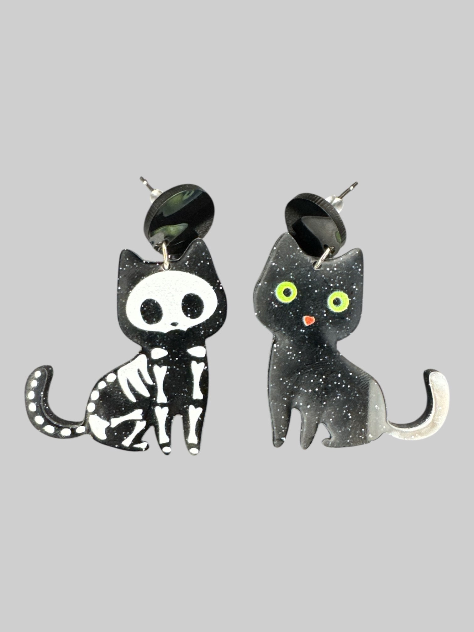 Pair of black cat earrings, one skeleton, one with green eyes
