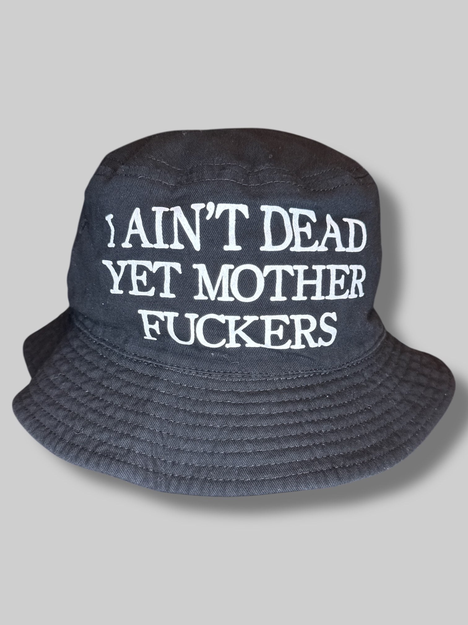 Black bucket hat with “I ain’t dead yet motherfuckers“ print