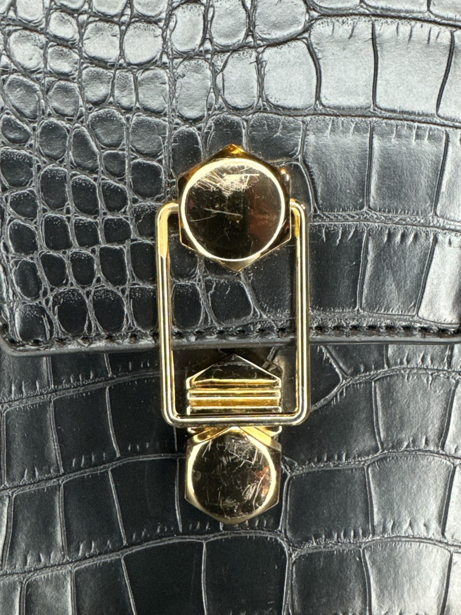 Black, small leather handbag with unique clasp, and D rings for a shoulder strap