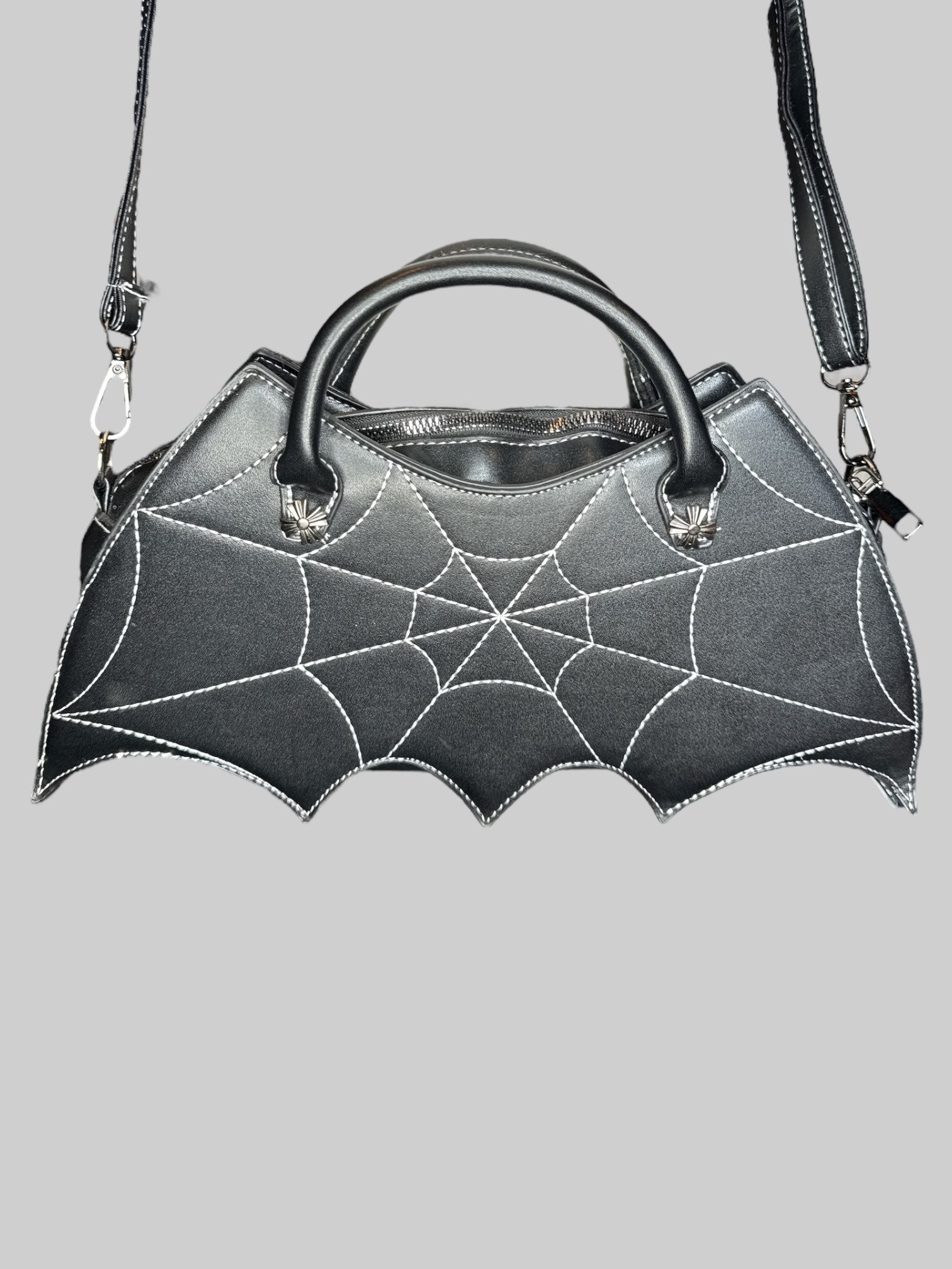 Black leather bat shaped handbag with spiderweb embroidery on front, an adjustable shoulder strap