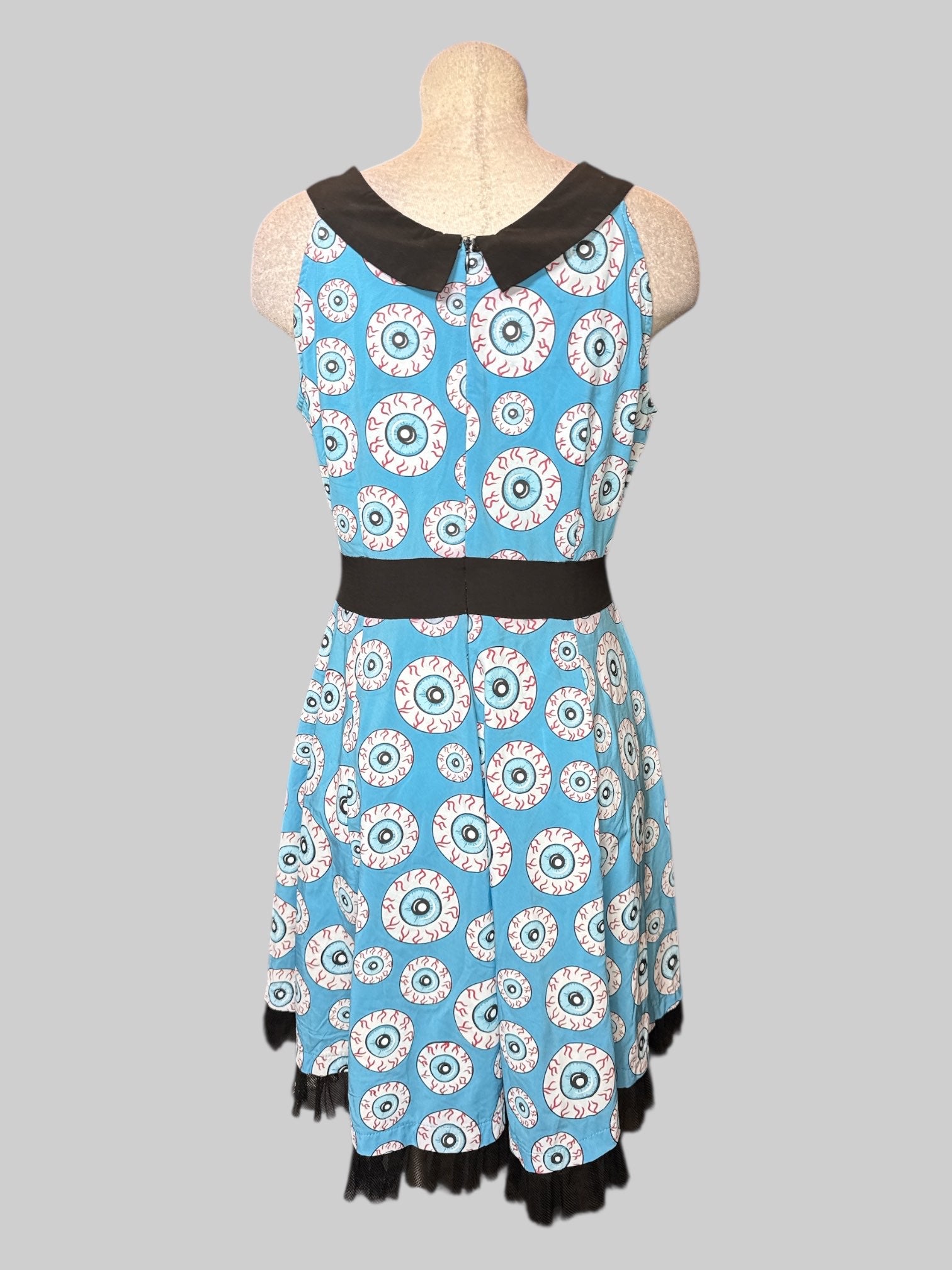 L blue sleeveless dress with eyeballs all over, faux bow on front, and zipper on back