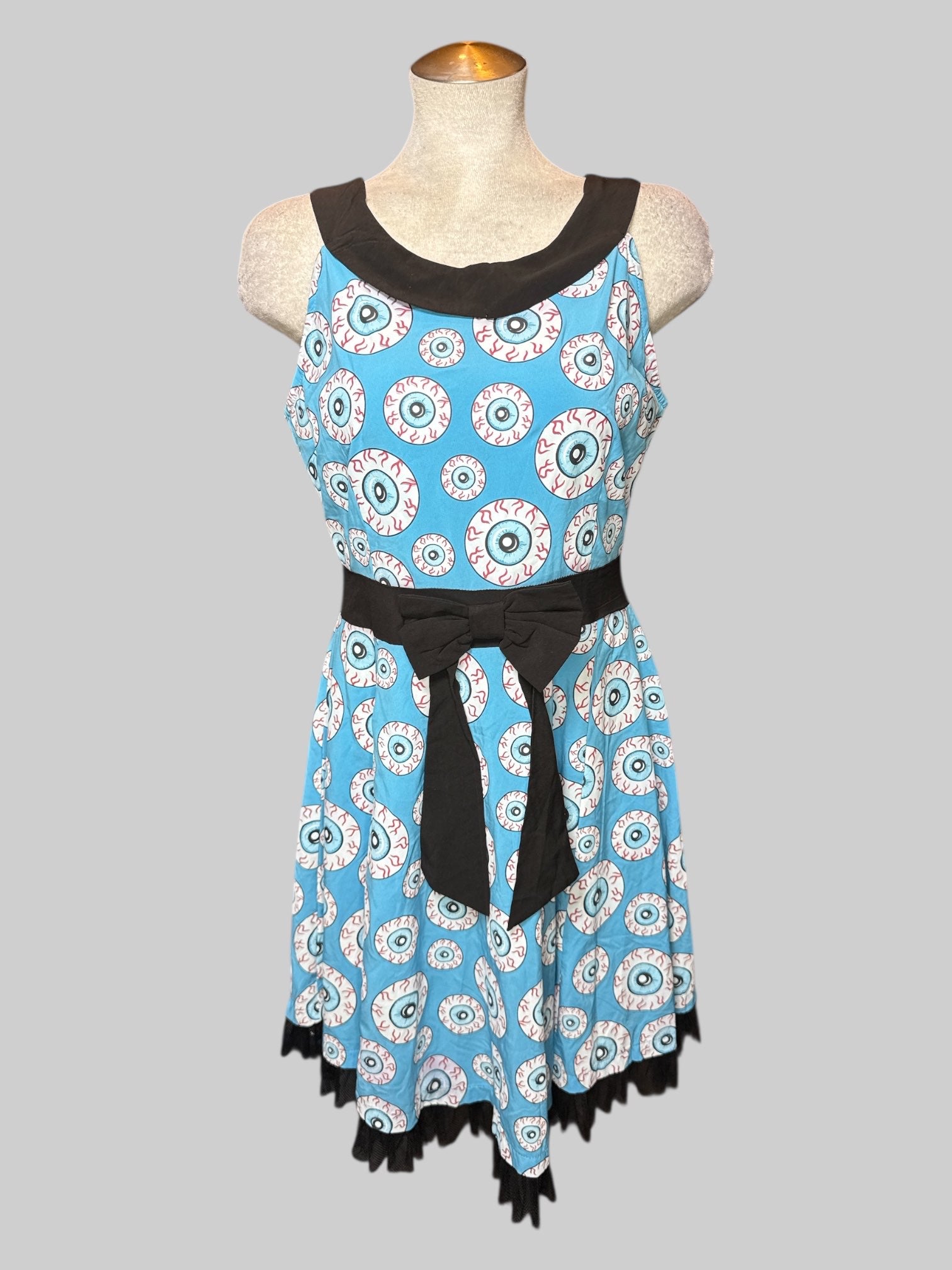 L blue sleeveless dress with eyeballs all over, faux bow on front, and zipper on back