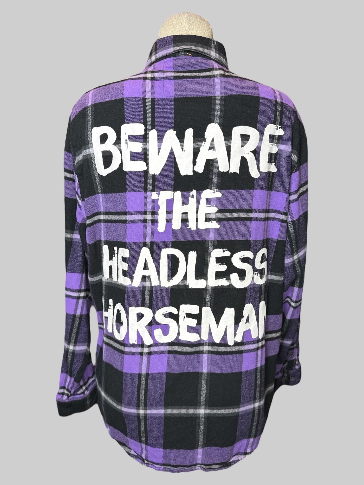 L purple and black plaid button down with Headless Horseman embroidery on front and sleeves, and “Beware the headless Horseman” graphic on back