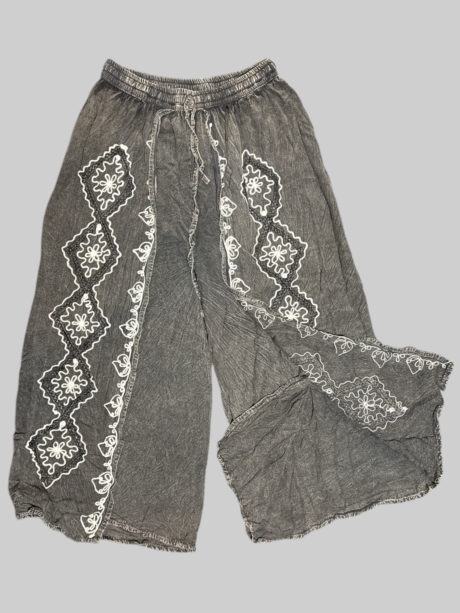 L black faded, split pants with black and white embroidery on front, drawstring, and stretchy waistband