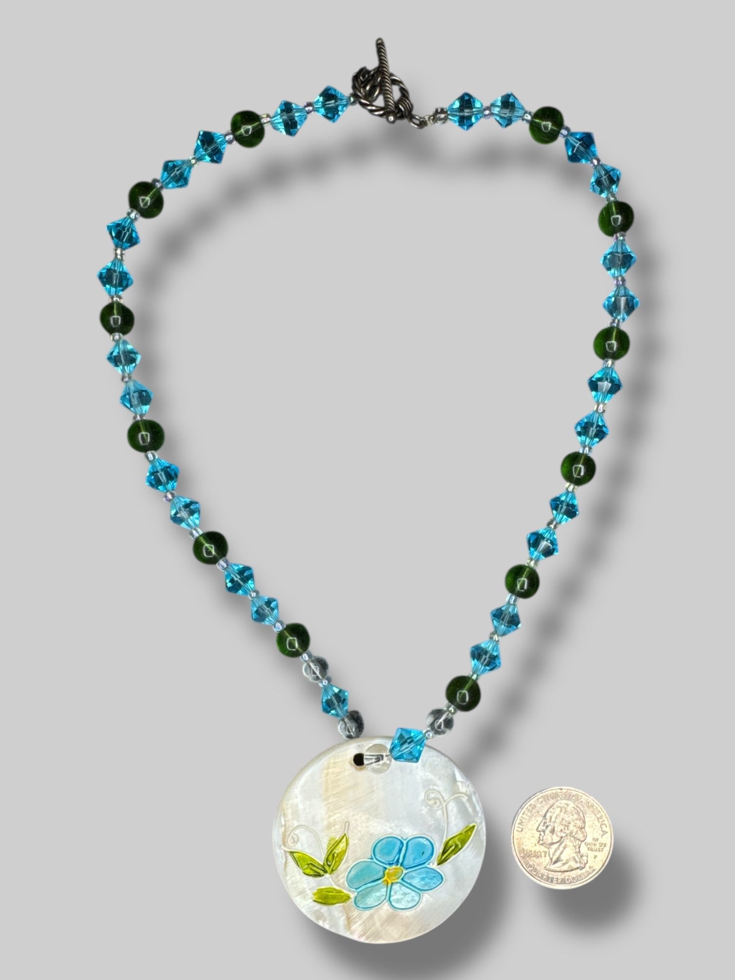 Blue, clear, and green beaded necklace with a shell flower pendant