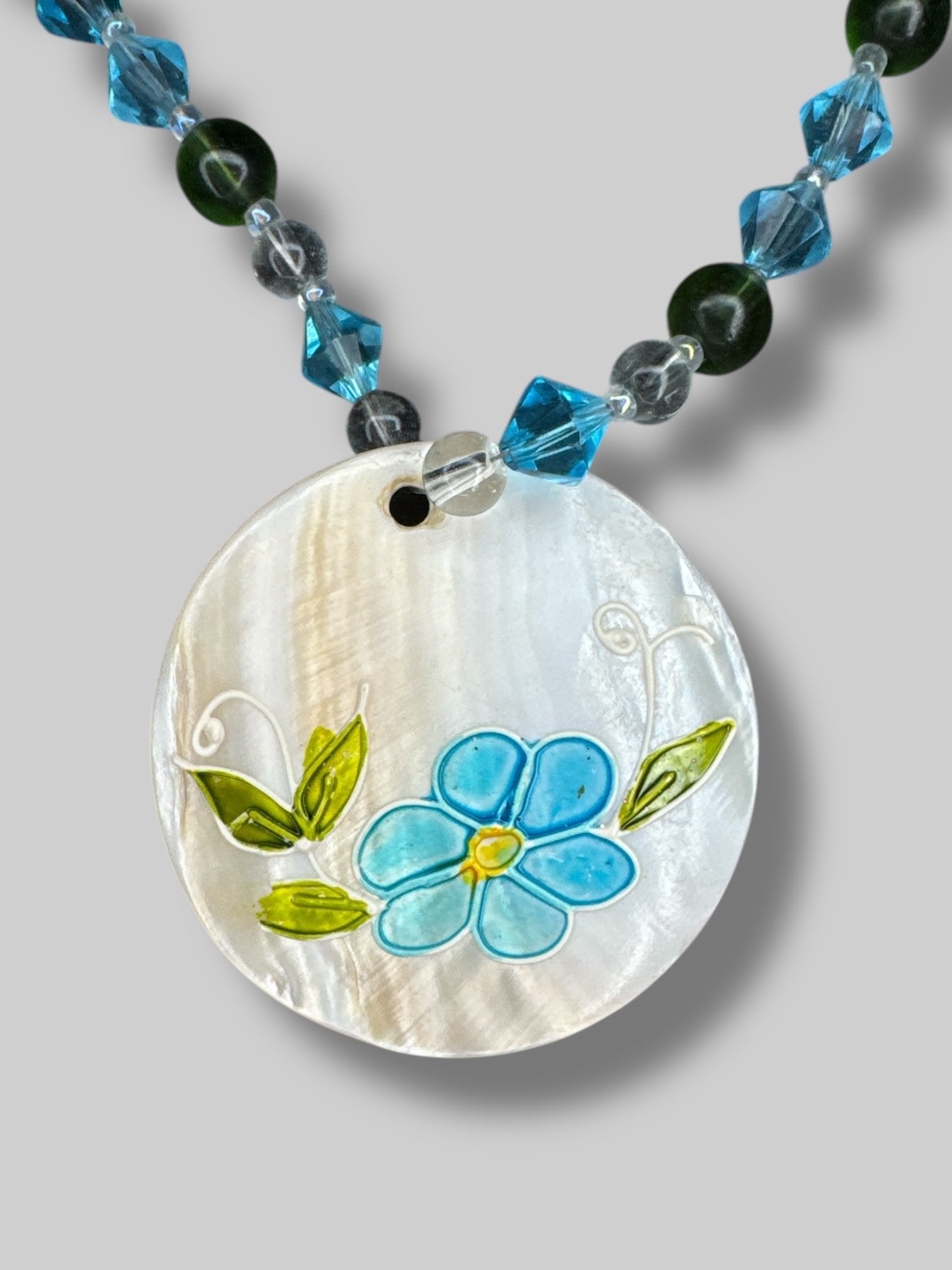 Blue, clear, and green beaded necklace with a shell flower pendant
